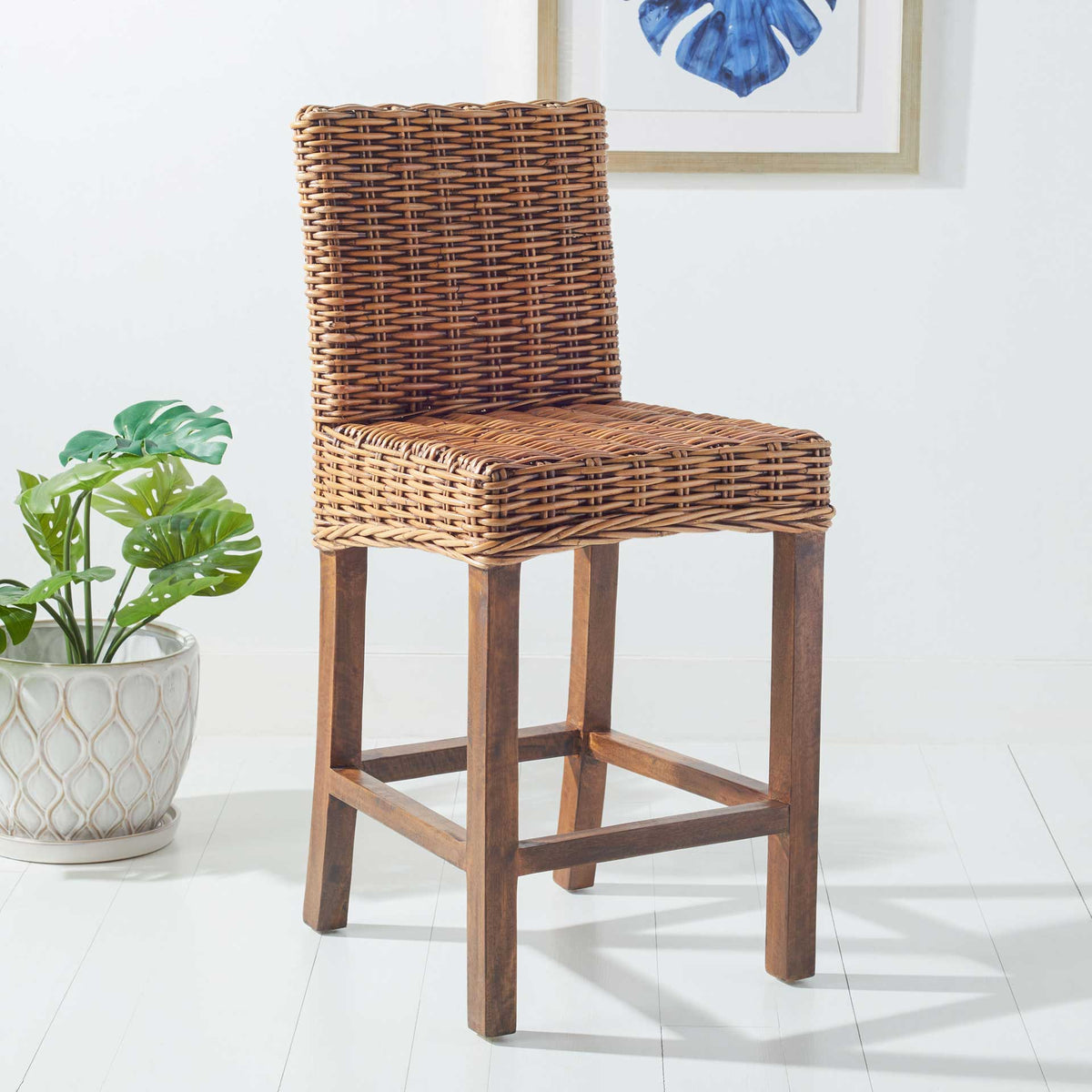 Honey-brown woven counter stool brings rustic warmth beside green foliage