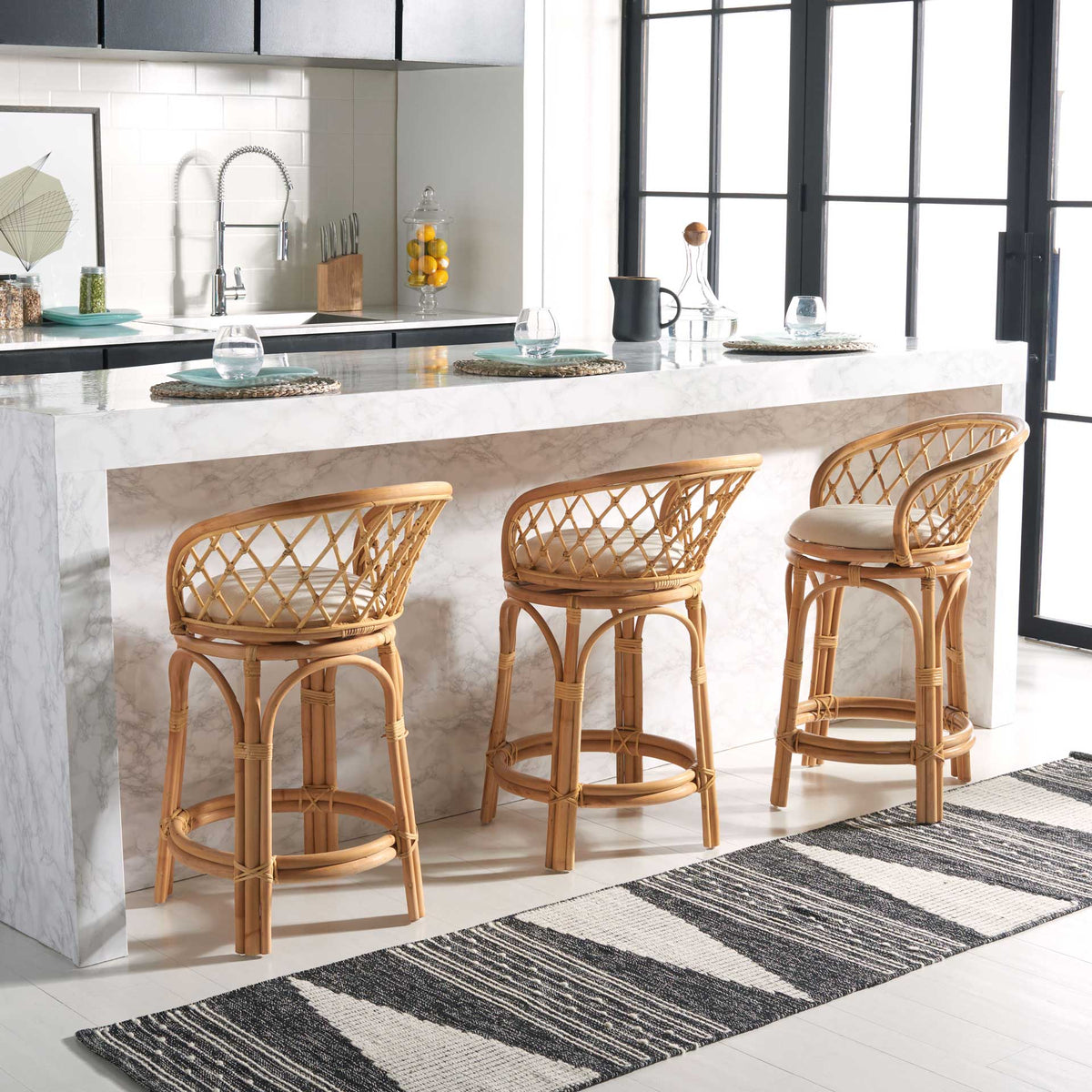 Natural rattan stools bring warmth and open latticework to a bright kitchen island