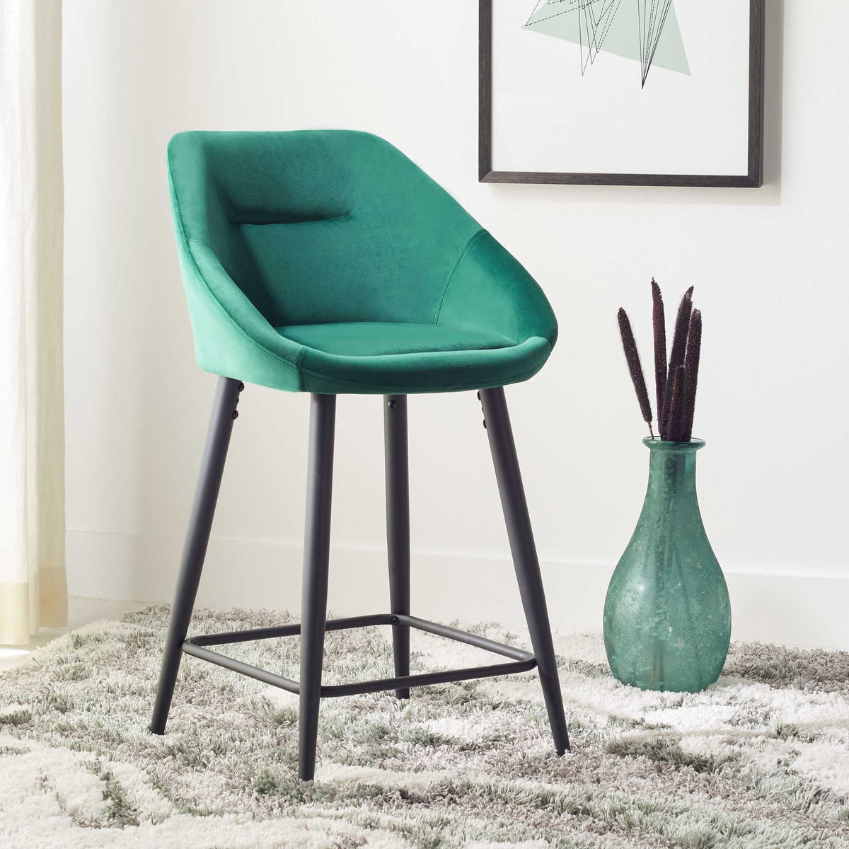 Plush emerald velvet counter stool pairs a wraparound seat with a sleek black metal frame