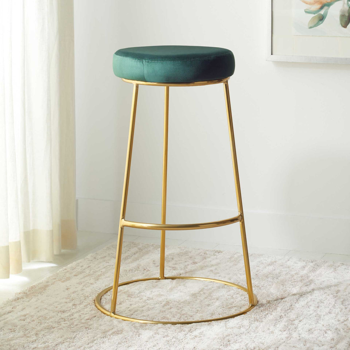 Deep green velvet and a slim gold frame brighten a cozy corner with a soft rug