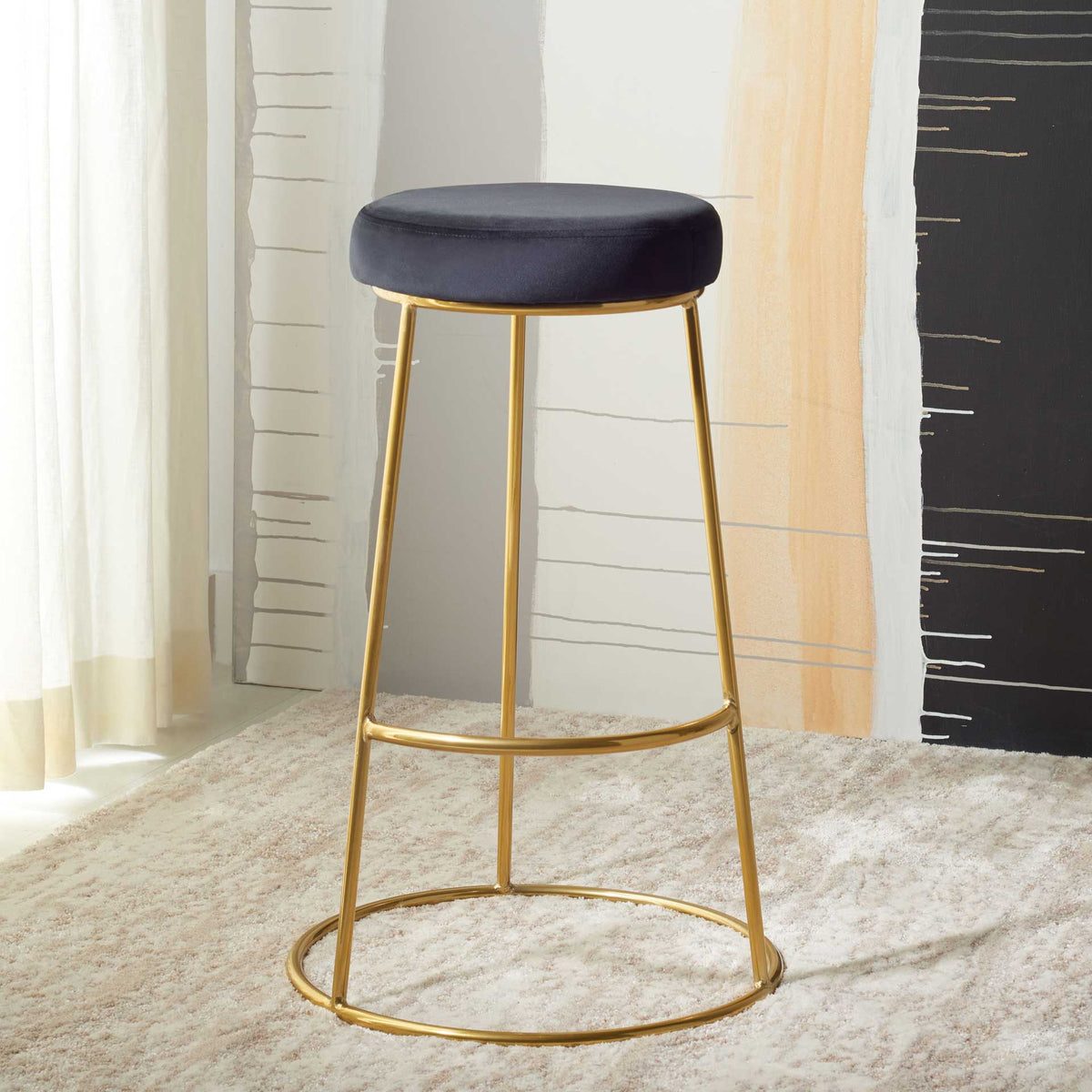 A black cushioned seat and open gold frame add a sleek accent atop a soft rug