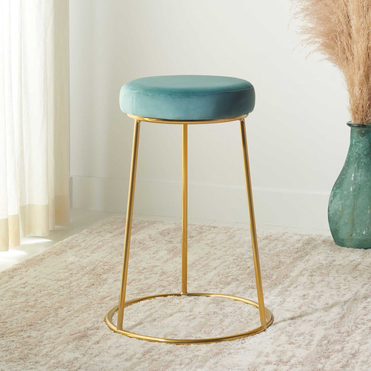 A fresh seafoam seat brings color to the stool's minimal gold frame and airy silhouette.