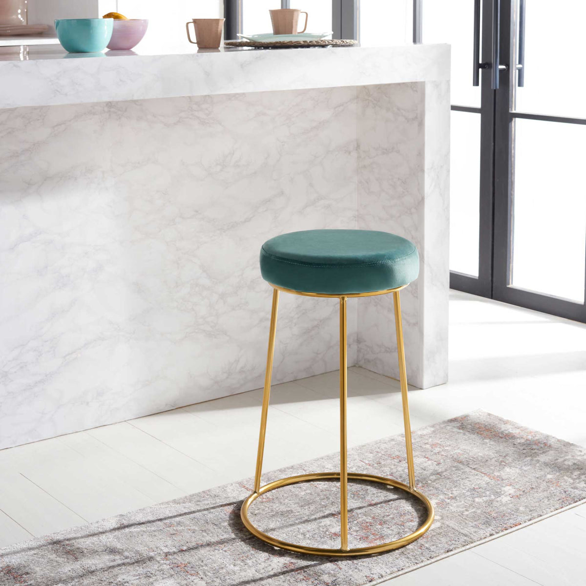 A plush seafoam cushion crowns a slender gold frame with a round, open base.