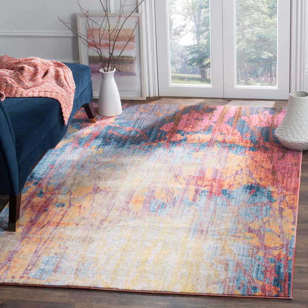 A painterly abstract rug in blue, rust and pink brightens a living room beside a deep blue sofa.