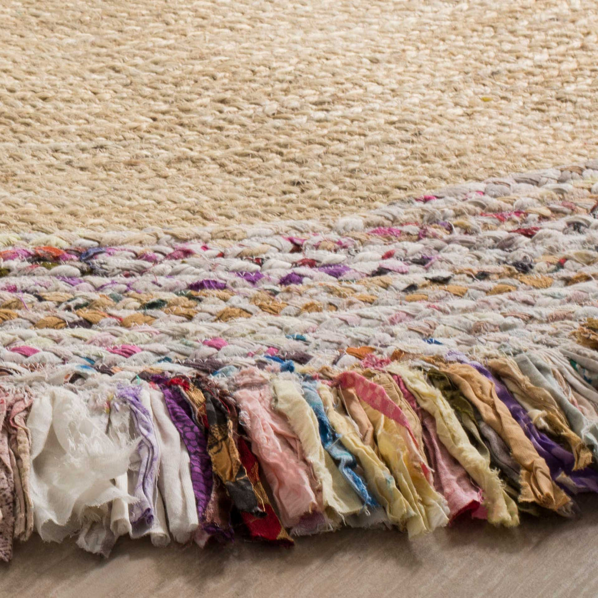 Colorful fabric fringe and flecked braids brighten the sandy jute surface of this rug.