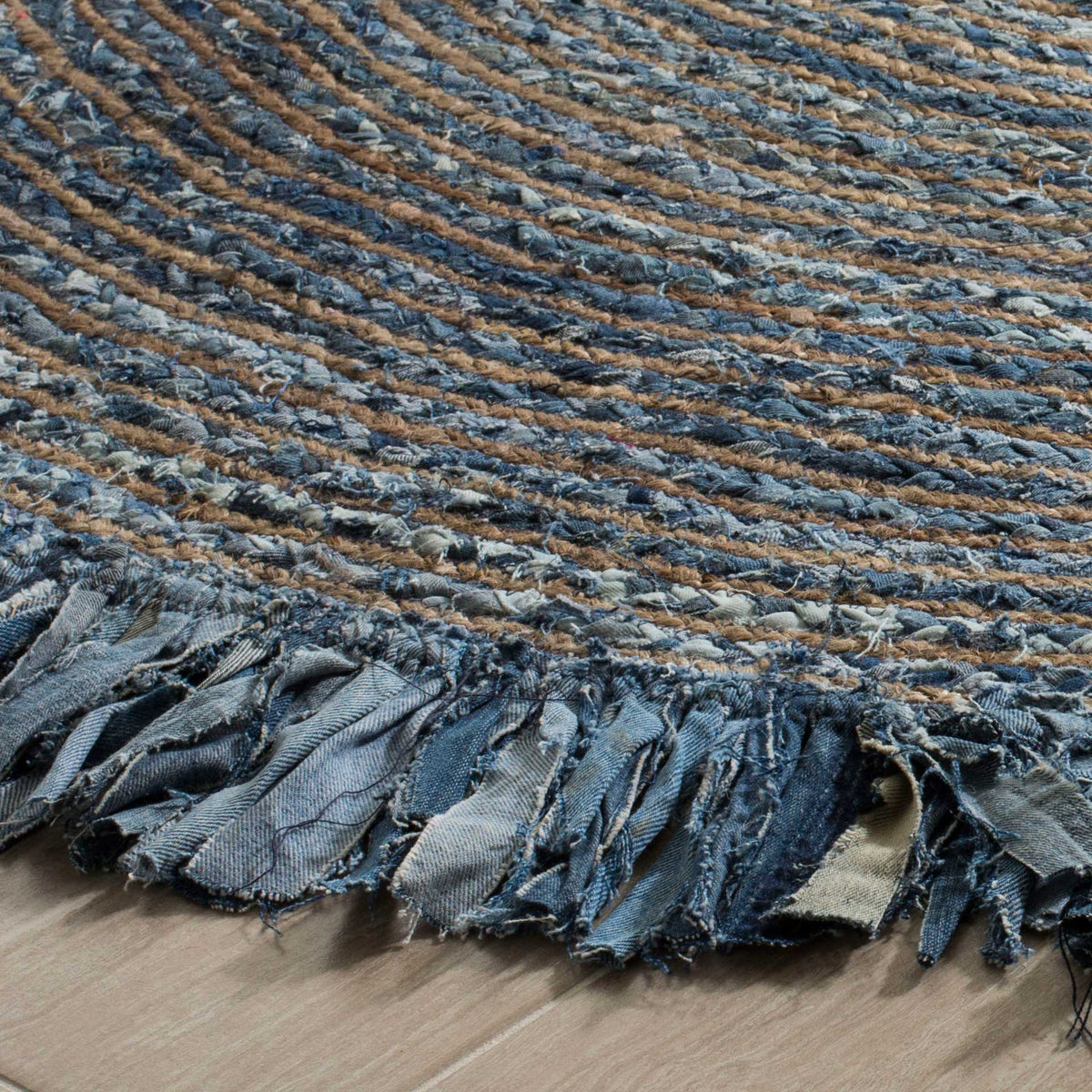 Blue and tan braids meet a richly textured denim fringe along this round rug's edge.