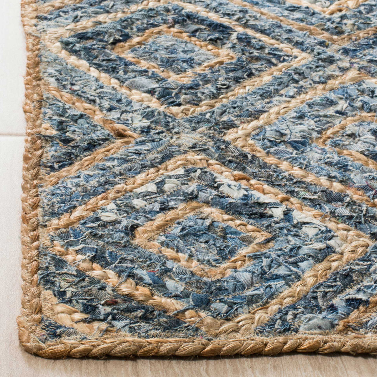 Rug edge reveals braided tan jute lines framing textured blue denim diamonds