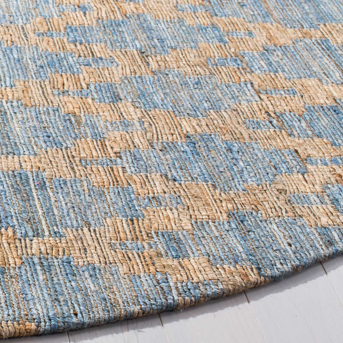 Textured blue and warm gold yarns weave subtle geometric motifs into a clean rug edge.