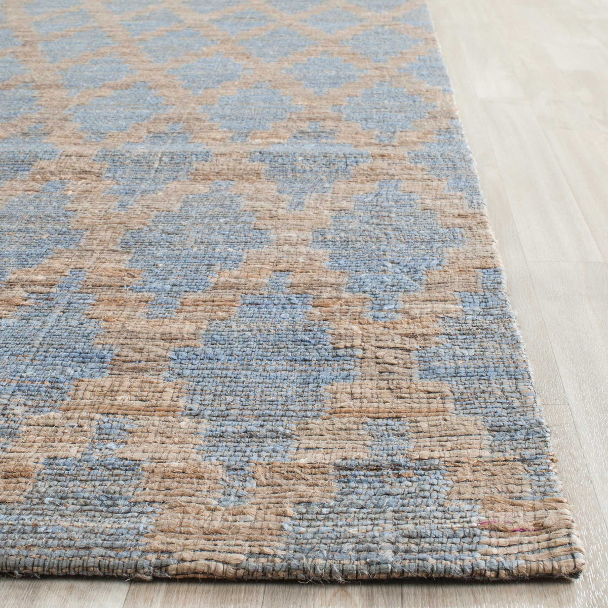Light blue woven motifs and natural gold outlines meet a neatly finished rug edge