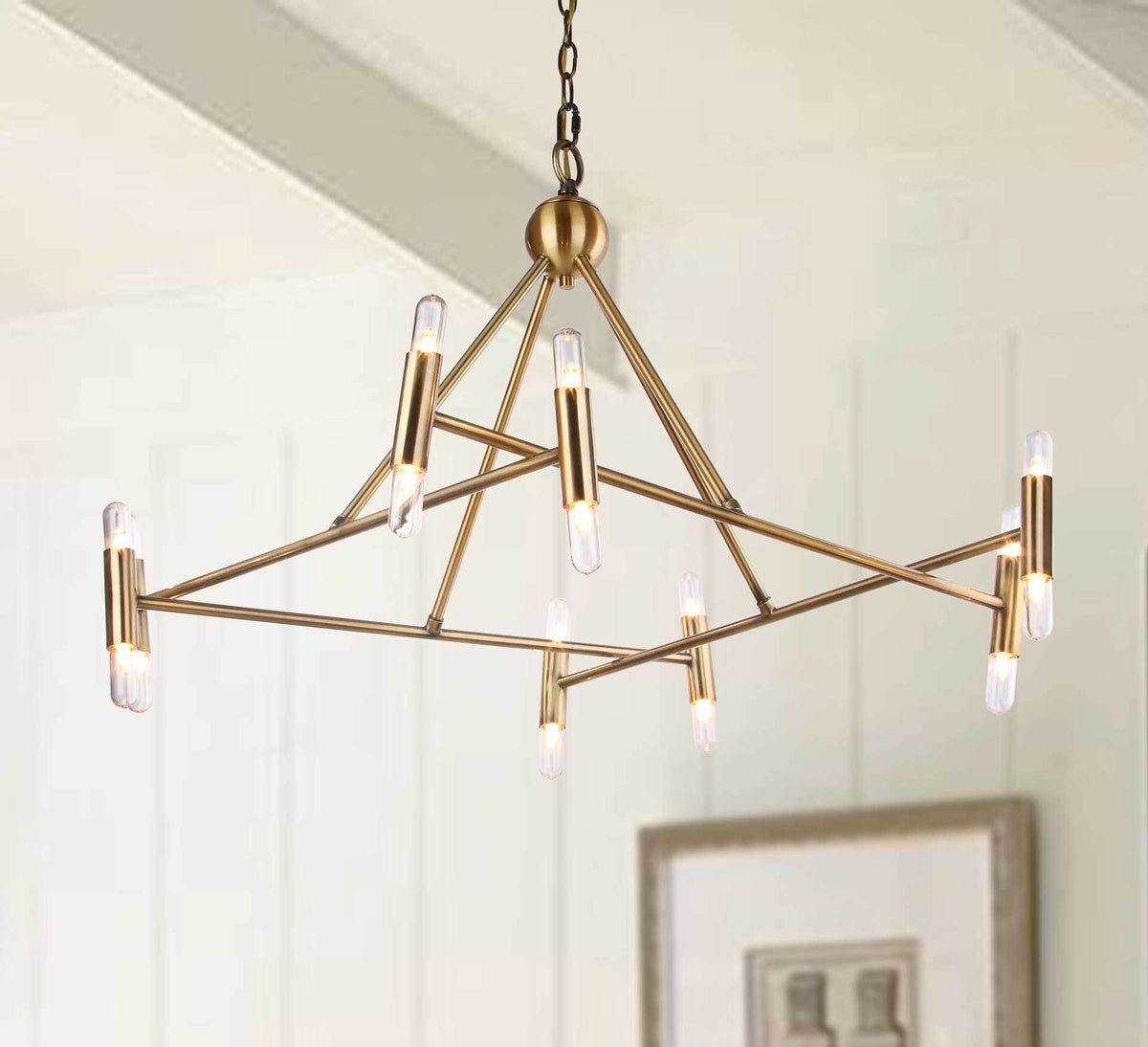Glowing bulbs bring warmth to an open, angular brass-finished chandelier in a bright interior