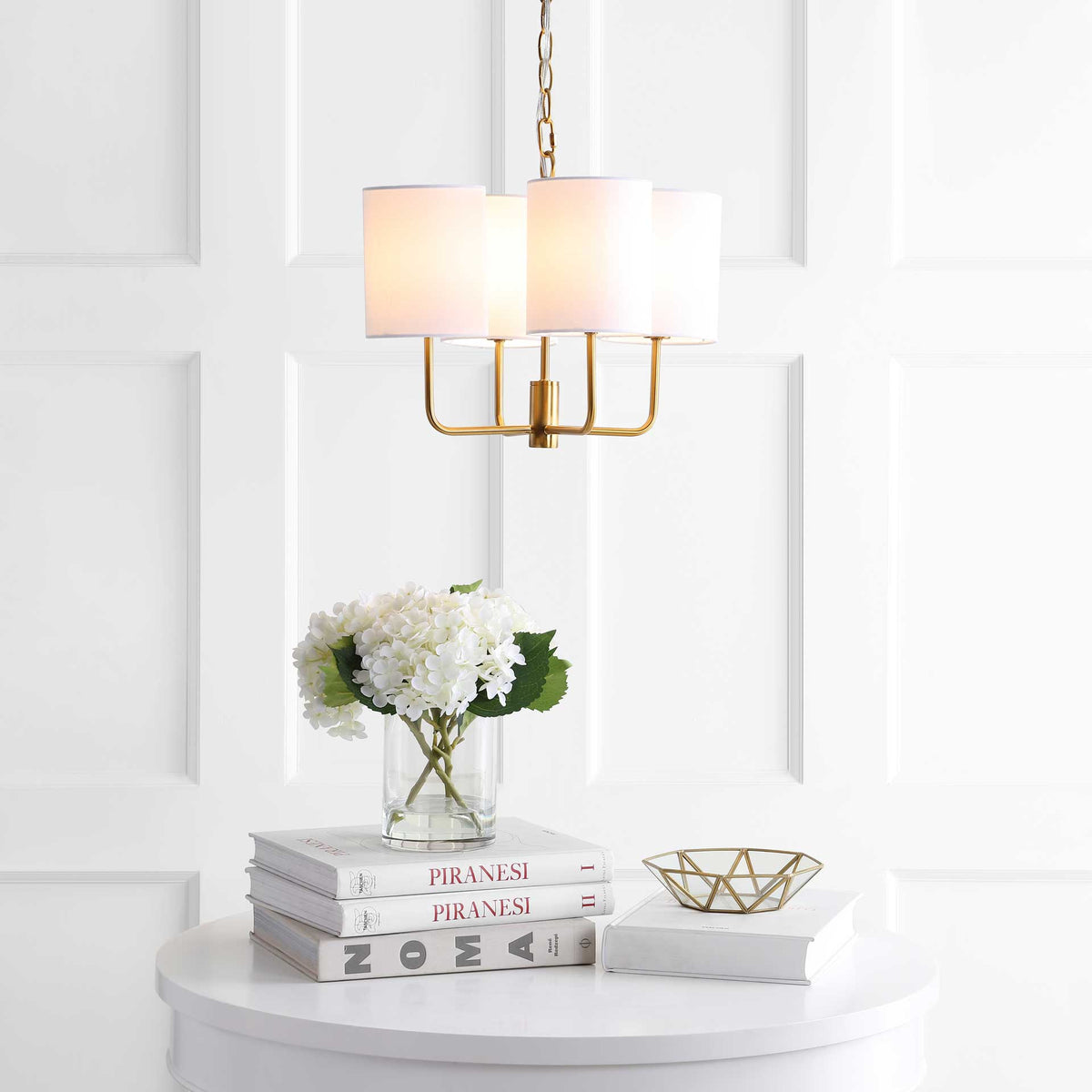 Glowing fabric shades bring warmth above a console with books and fresh flowers