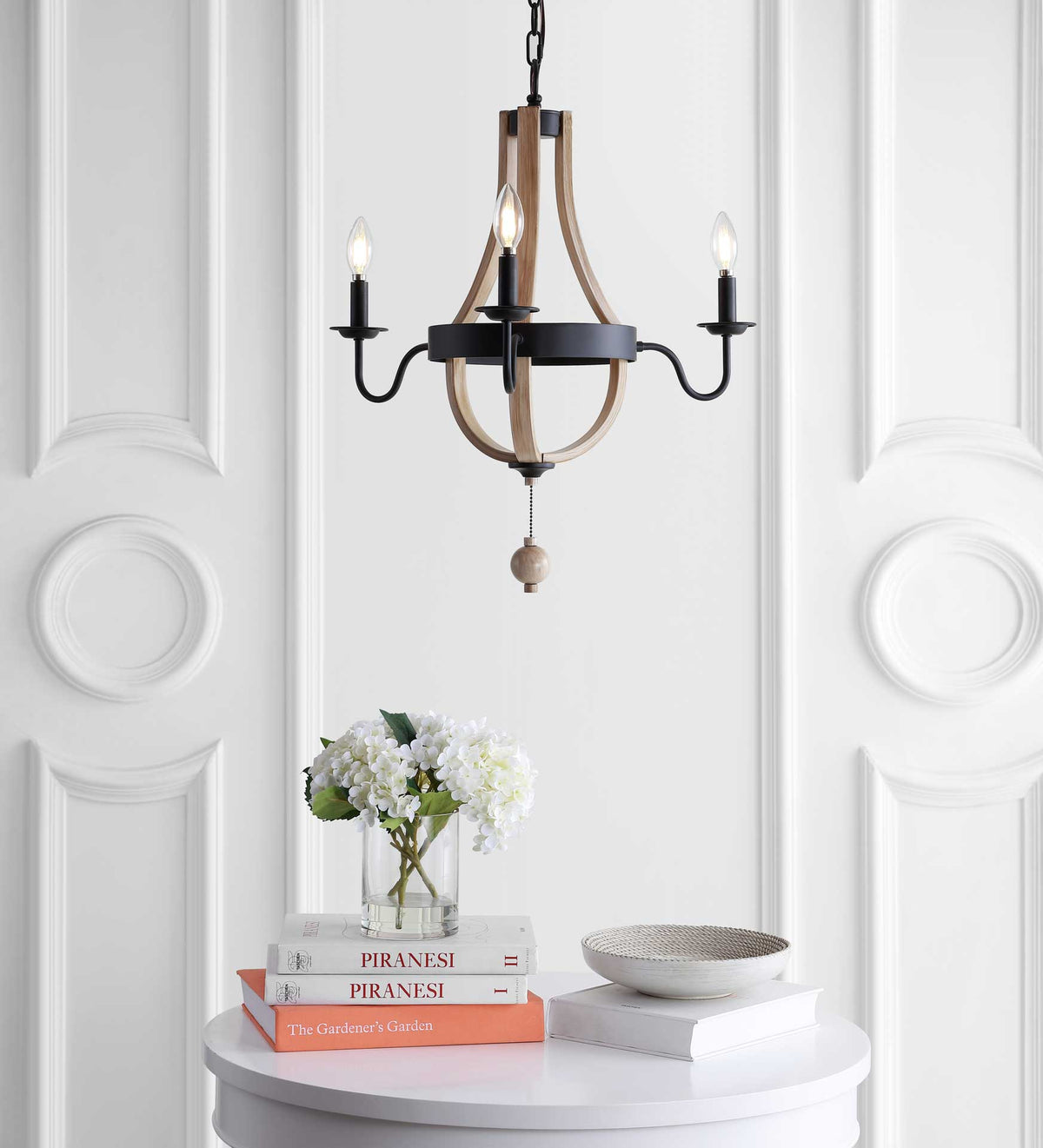 Warm light from three candle-style bulbs highlights a black circular frame and sweeping wood-look curves