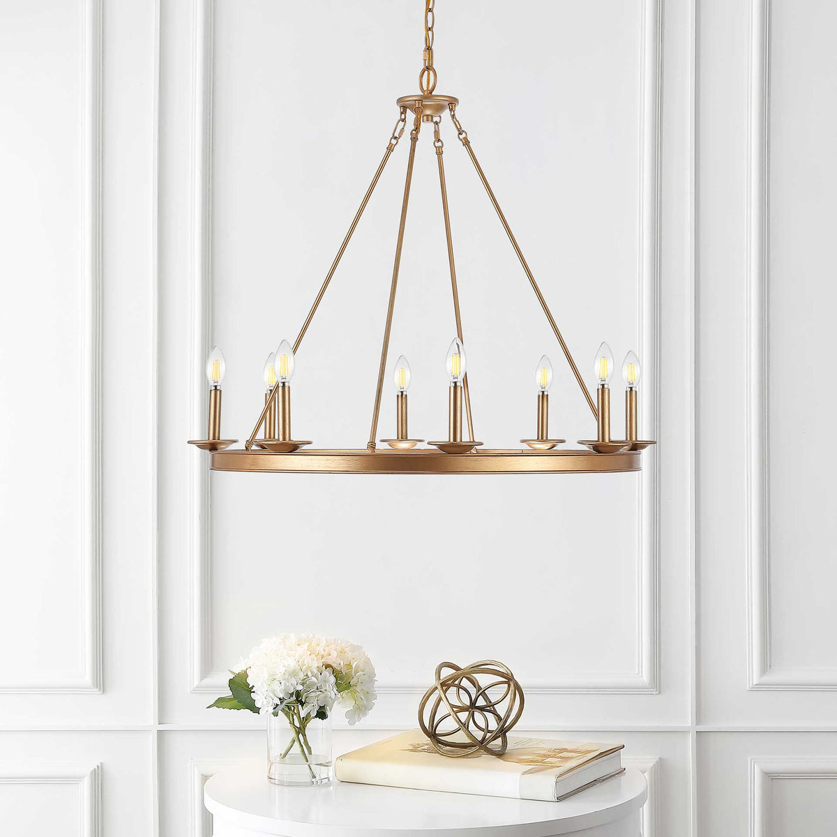 Warm candle-style lights illuminate a gold iron chandelier above a white table