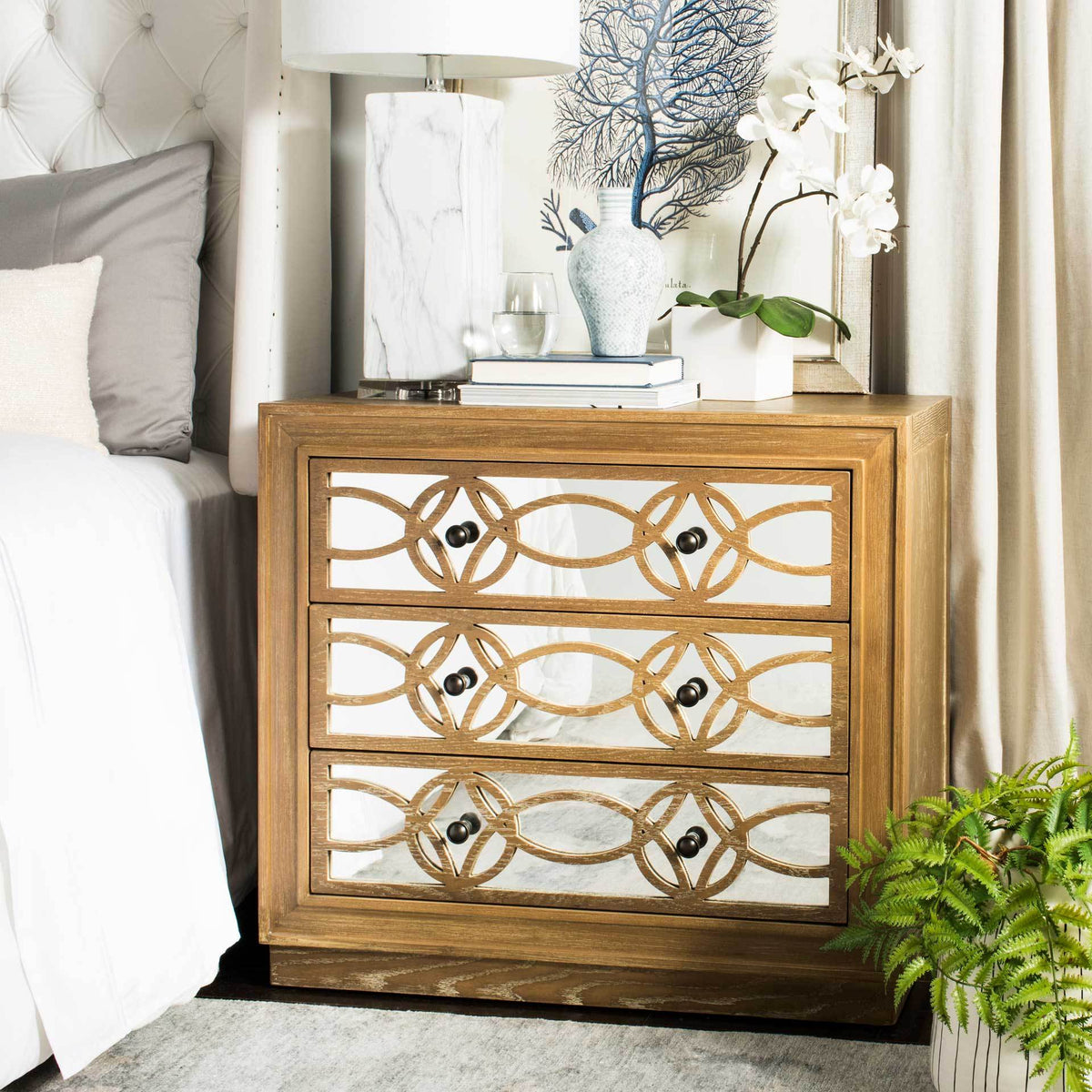Mirrored drawers with geometric oak trim lend texture and shine beside a bed.
