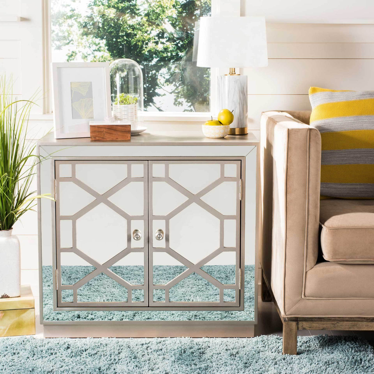 Champagne latticework frames two mirrored doors for an elegant accent beside a sofa.