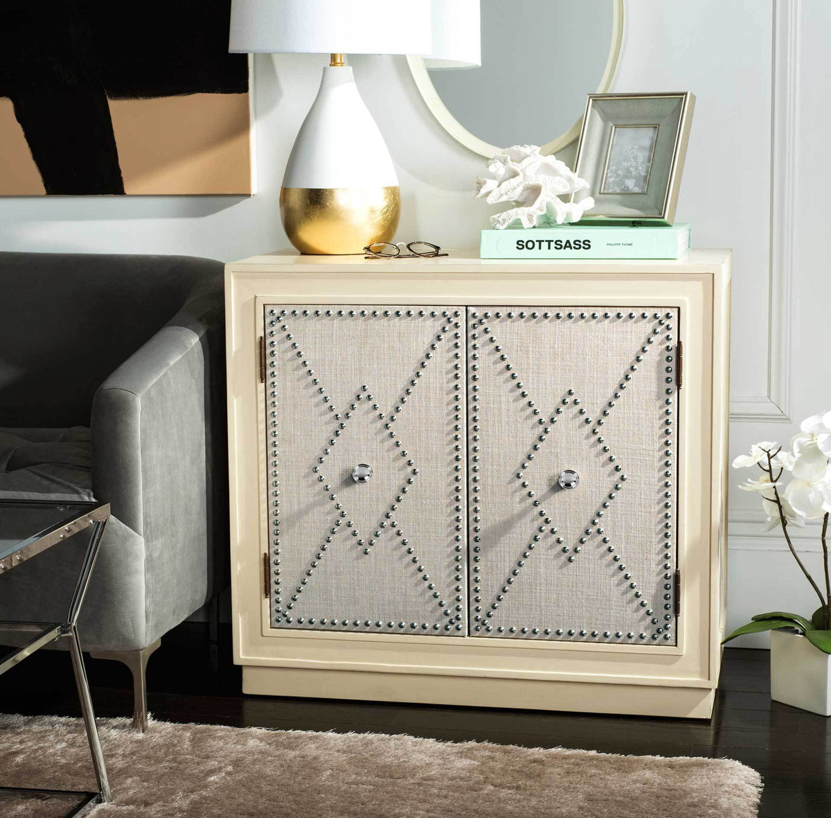 Metallic nailheads and round pulls lend sparkle to gray linen doors beneath a styled display top