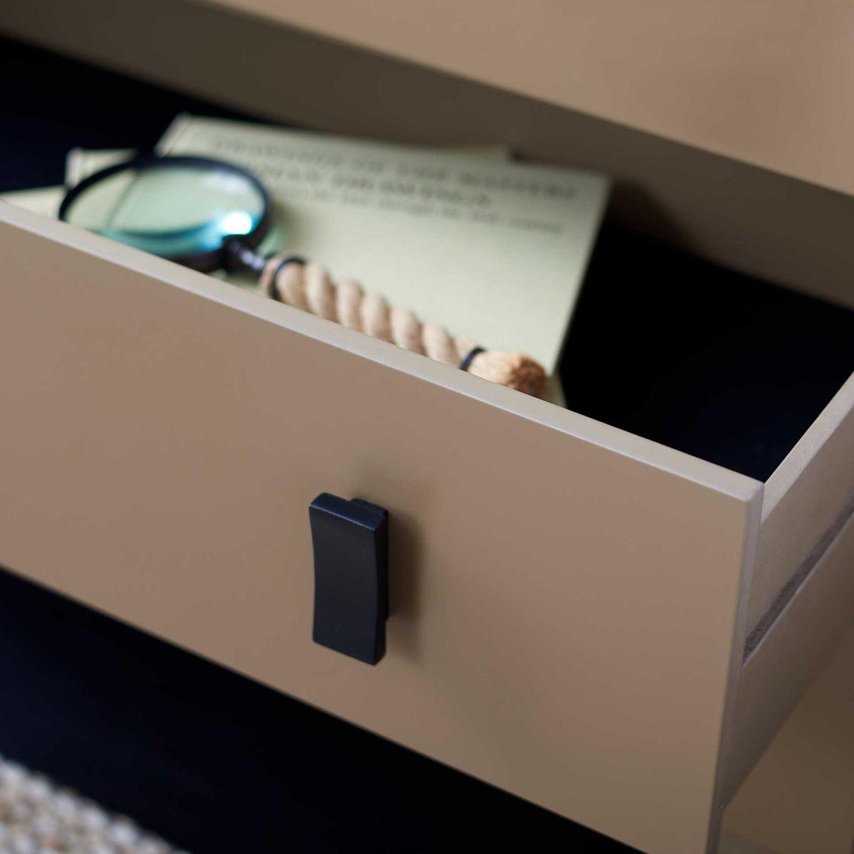 An open taupe drawer holds everyday essentials, with a bold black pull for easy access