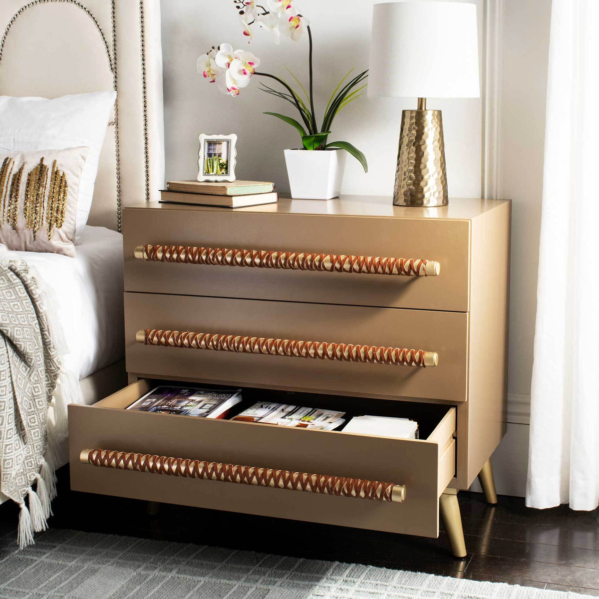 An open bottom drawer reveals handy storage in a taupe chest with brown-laced gold pulls