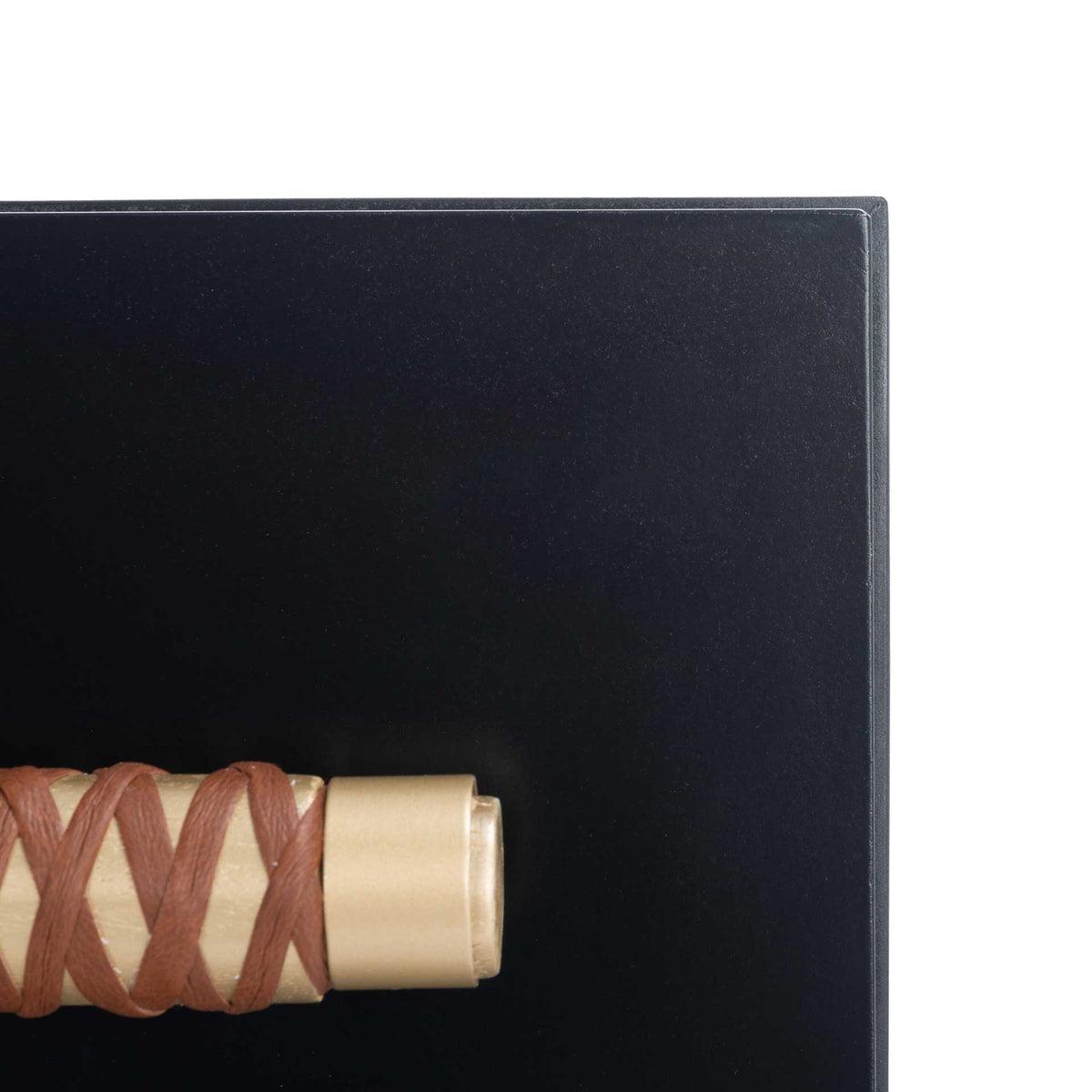 Gold-capped drawer hardware with brown faux leather lacing stands out against a smooth black finish