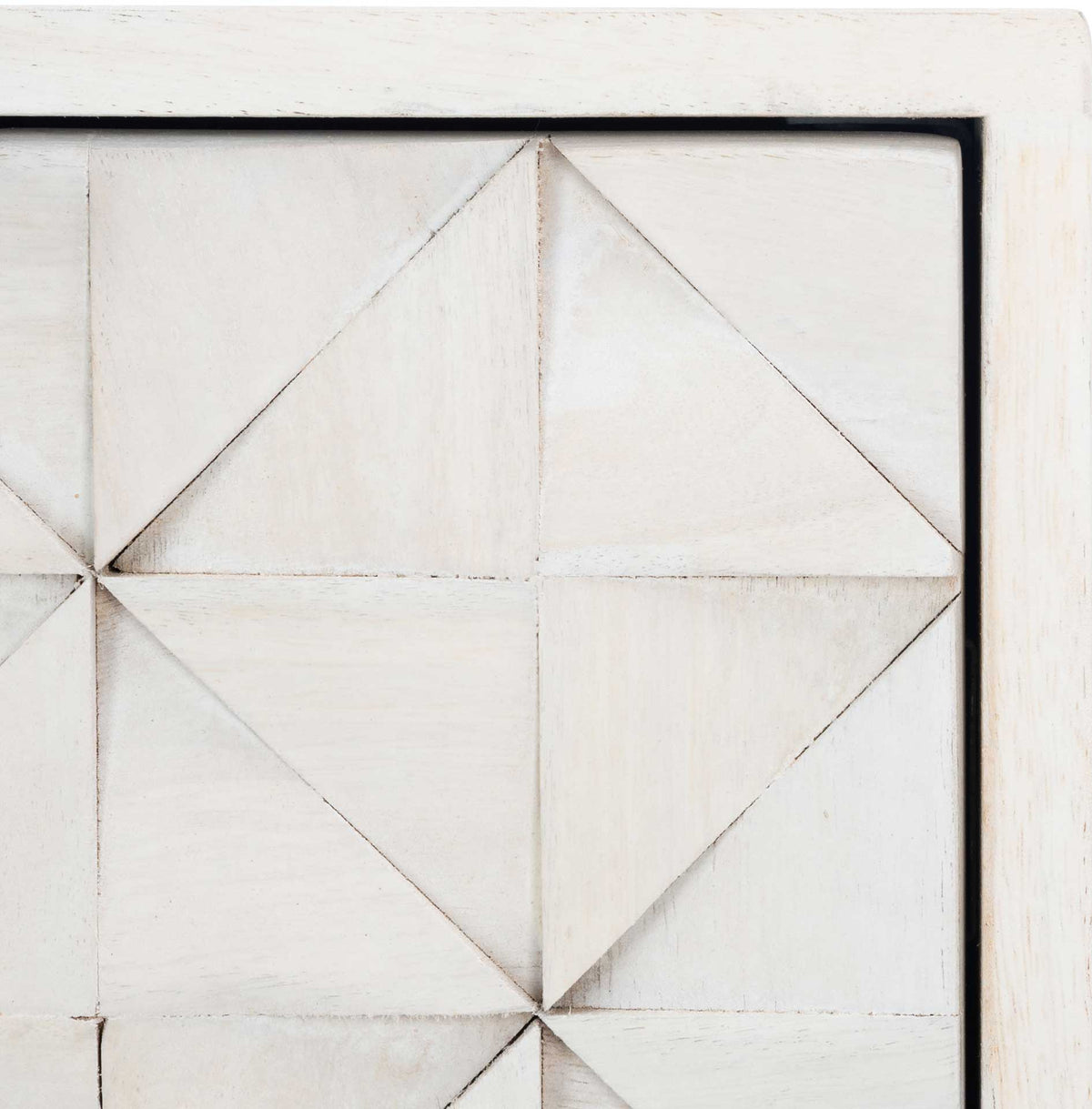Raised geometric carvings add crisp texture to the whitewashed wood.