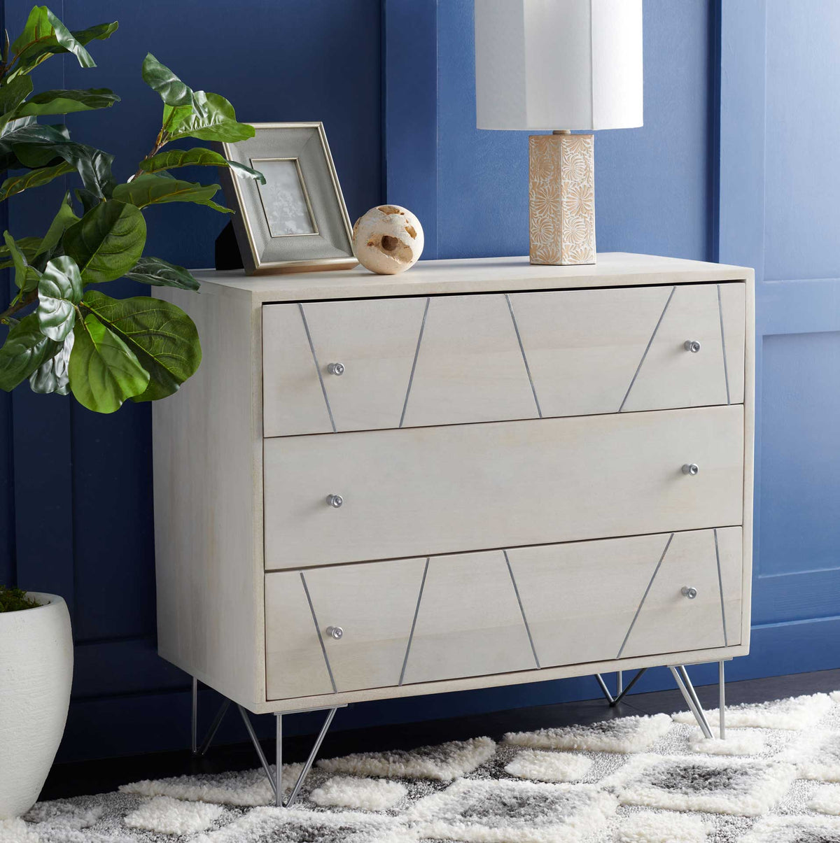Three whitewashed drawers with silver accents bring understated storage to a richly colored room.