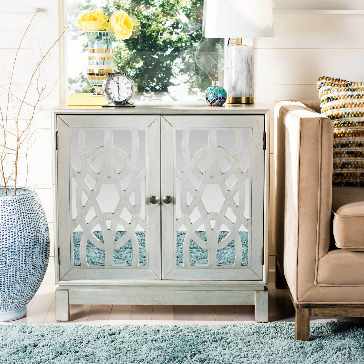 A broad display top and decorative lattice doors make this silver wood chest an elegant storage accent.