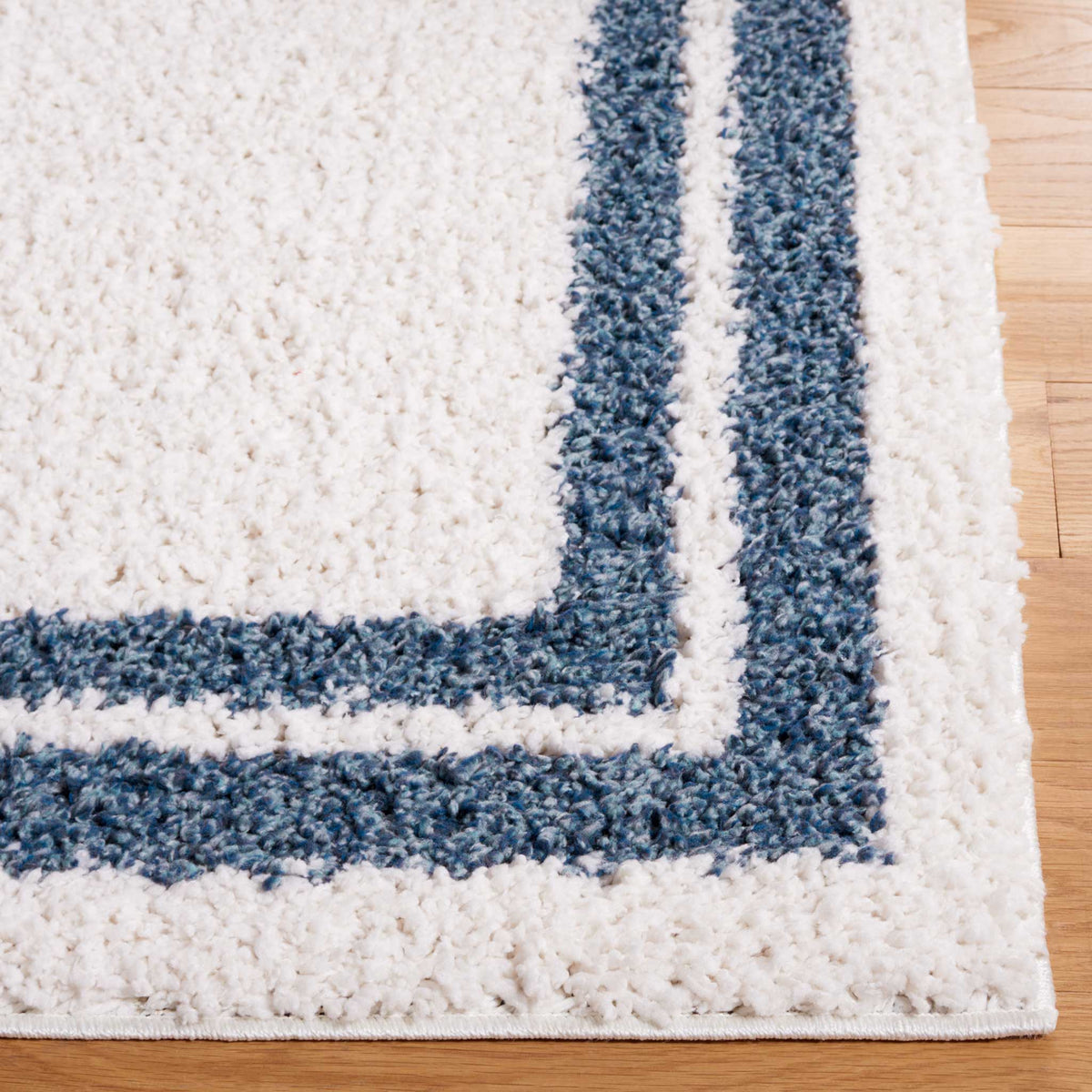 Soft ivory pile and bold blue border lines lend the rug striking definition