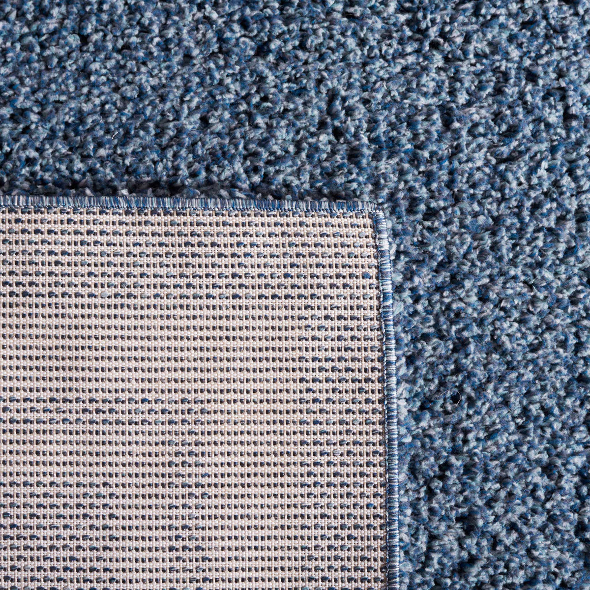 A woven backing supports the soft blue shag and its neatly bound edge