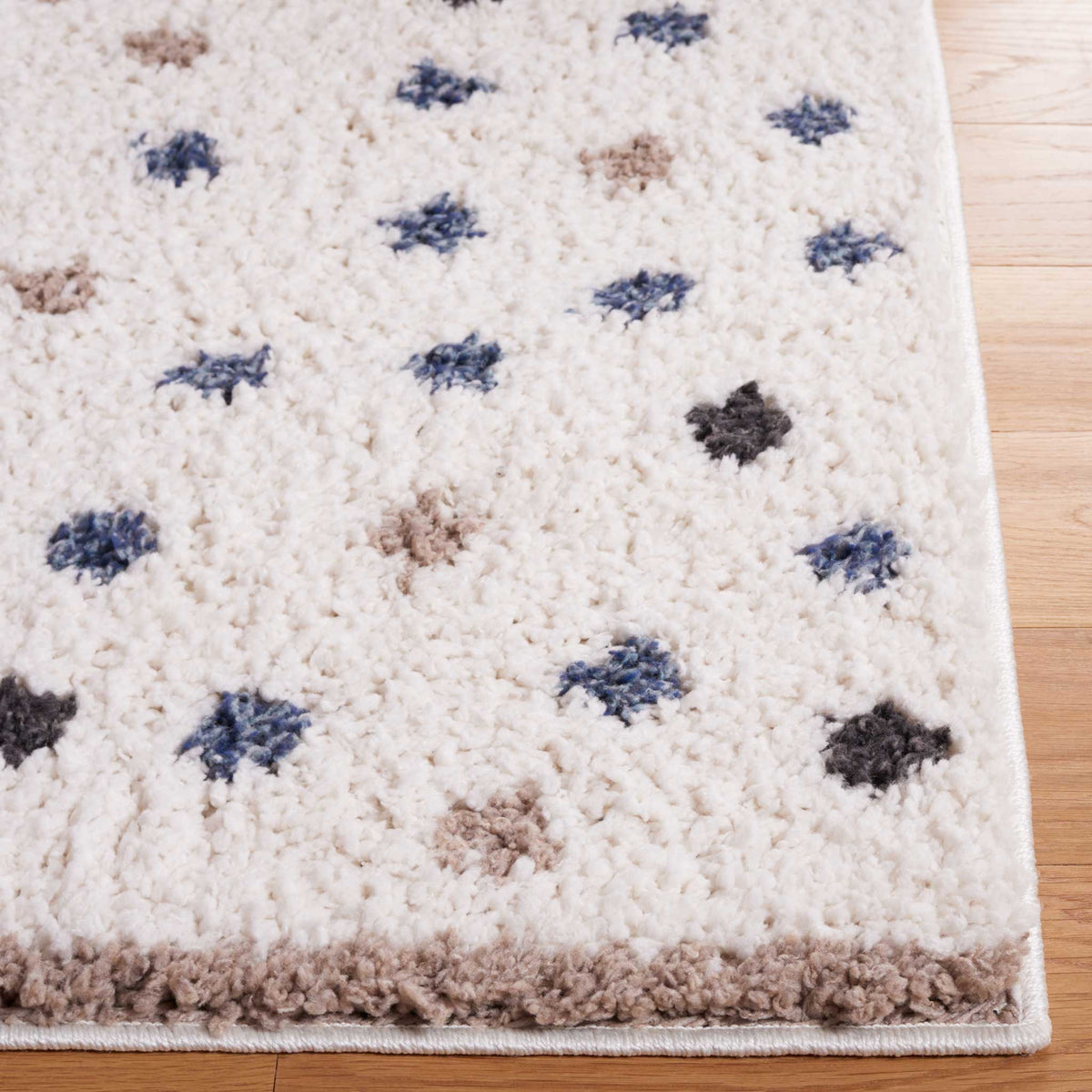 Soft ivory pile and scattered blue and taupe dots brighten the rug's edge