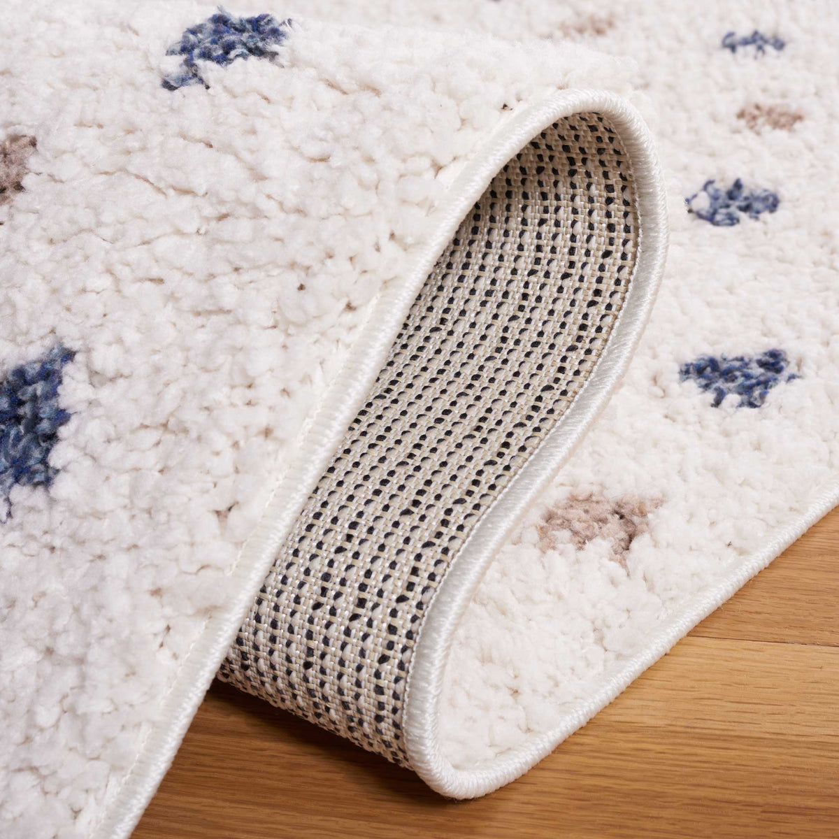 A folded ivory shag edge reveals its woven backing and plush pile