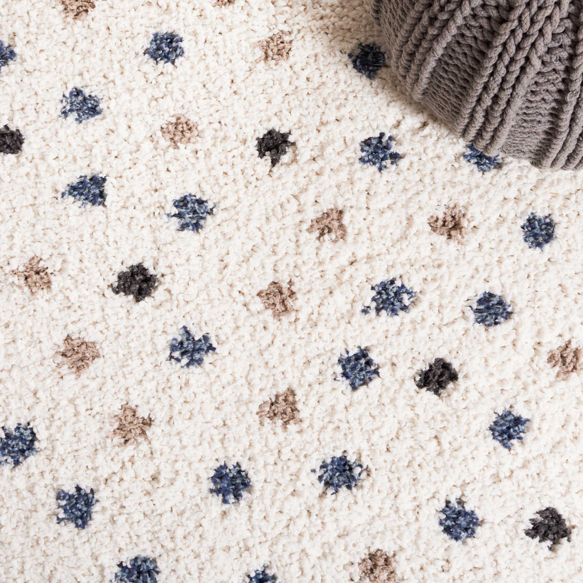 Blue, taupe, and charcoal dots dance across a fluffy ivory surface