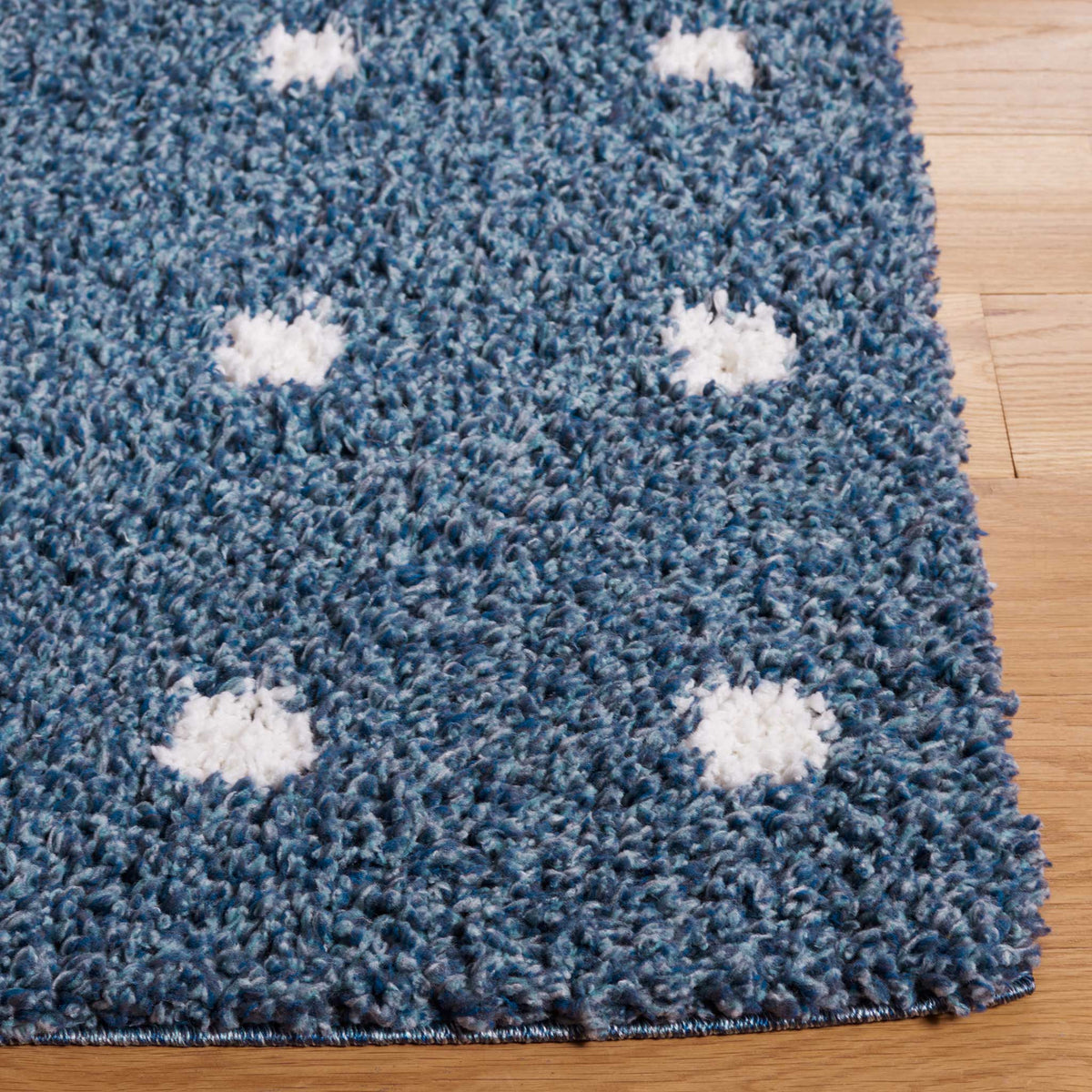 Ivory dots pop against thick blue shag along the rug's finished edge