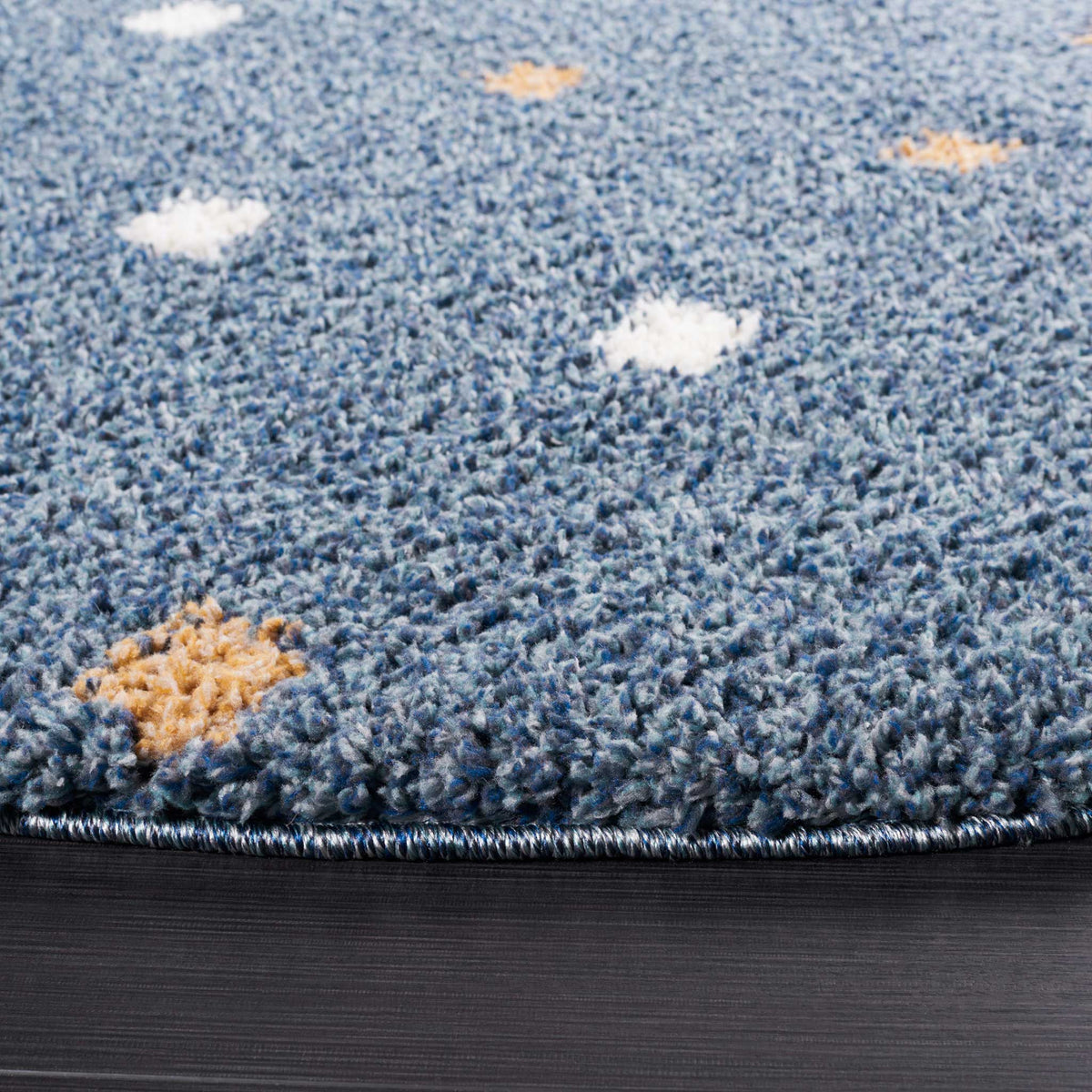 Thick blue shag pile surrounds fluffy ivory and golden dots near the bound edge