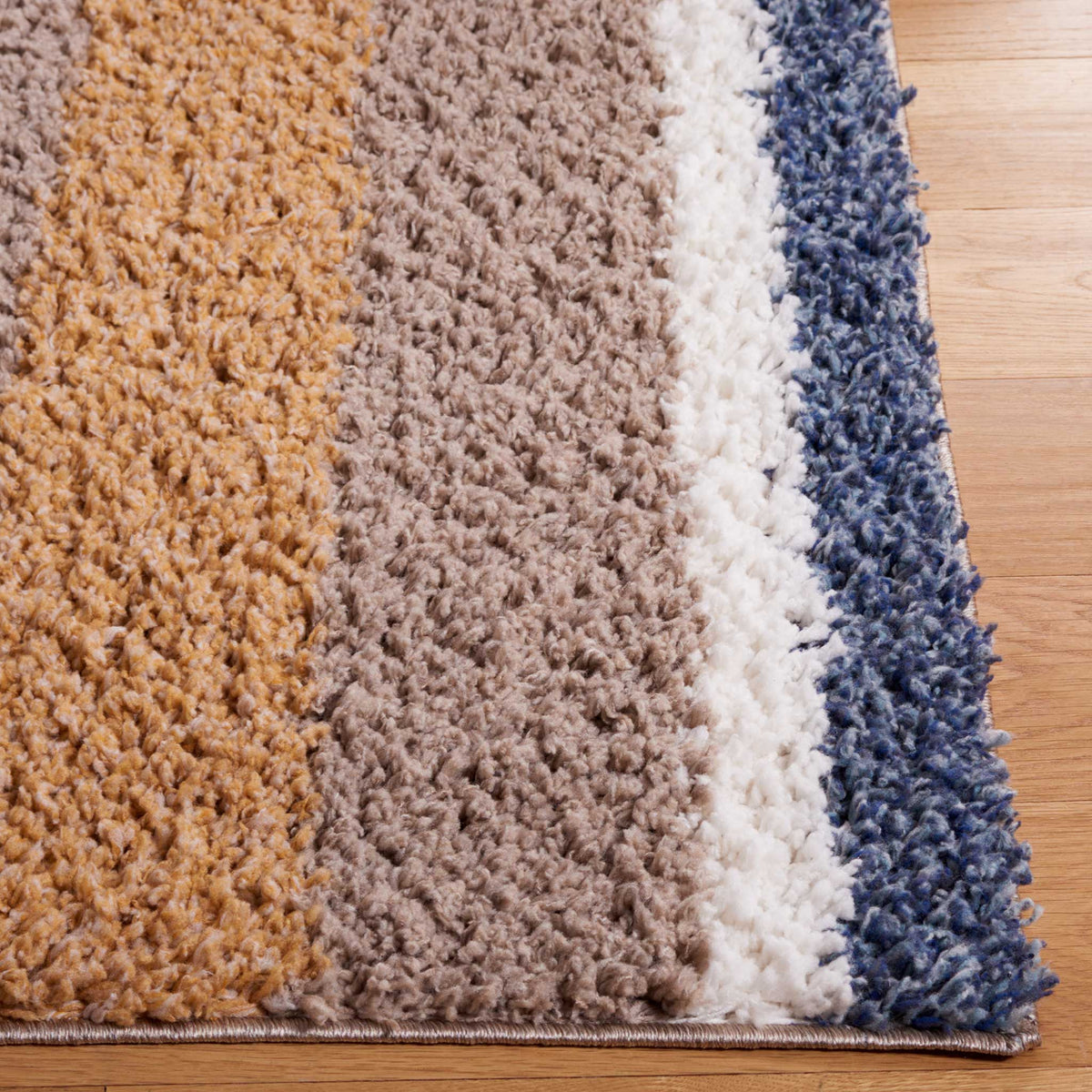 Blue, ivory, taupe, and warm tan stripes meet at a thick shag edge