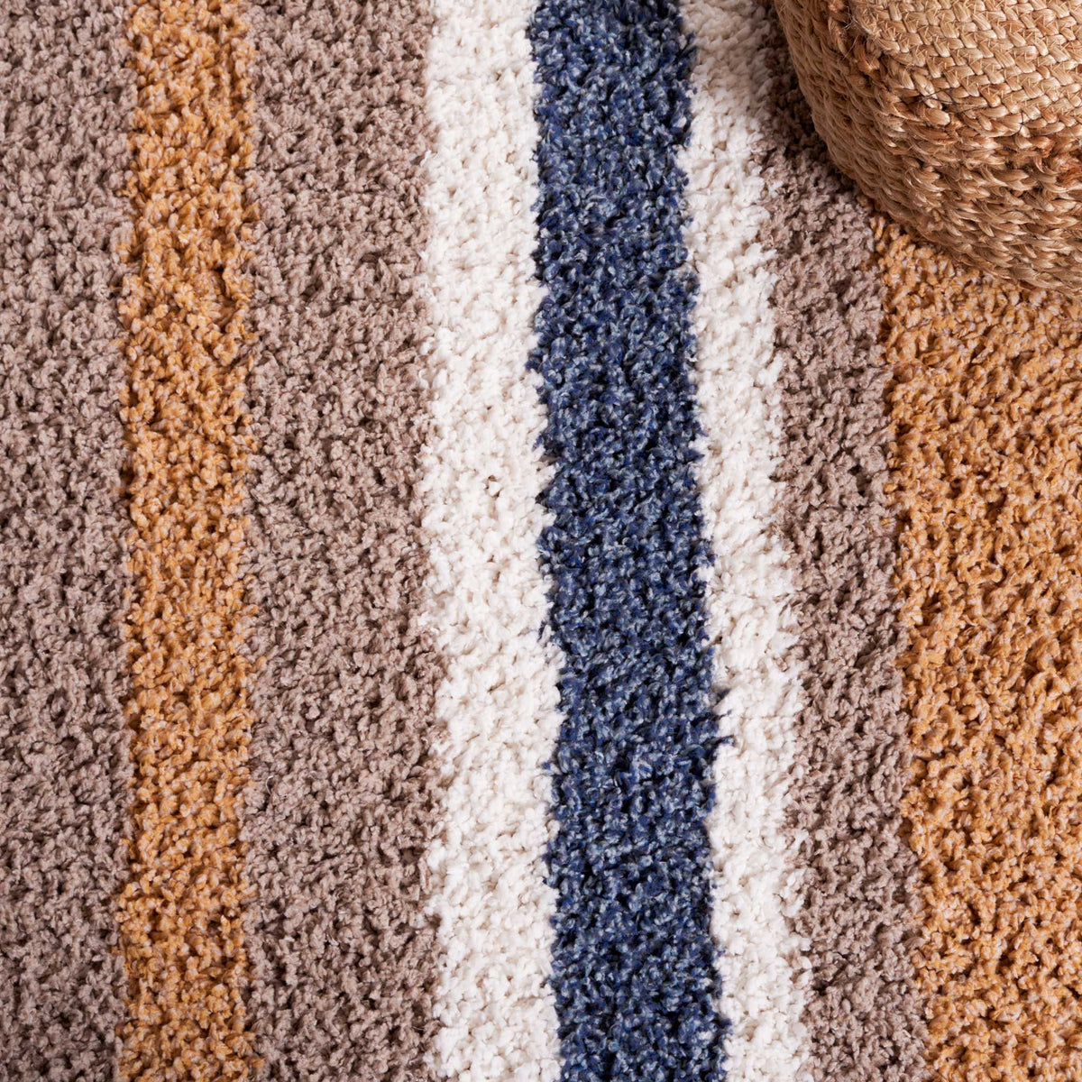 Lush striped shag pairs cool blue and ivory with warm taupe and gold