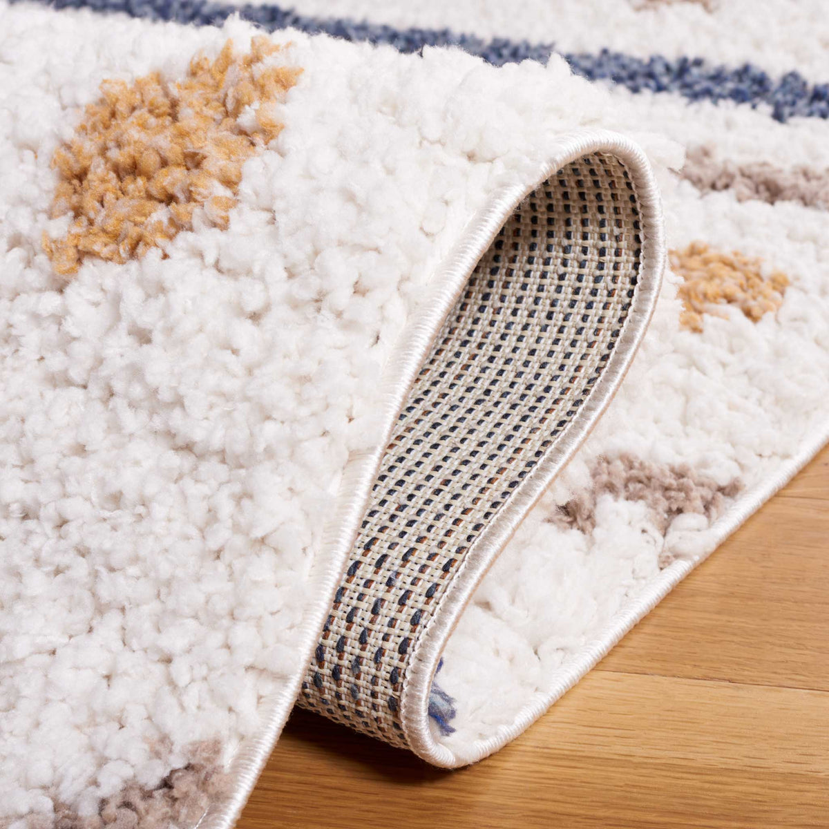 Folded ivory shag exposes woven backing beneath colorful dotted accents