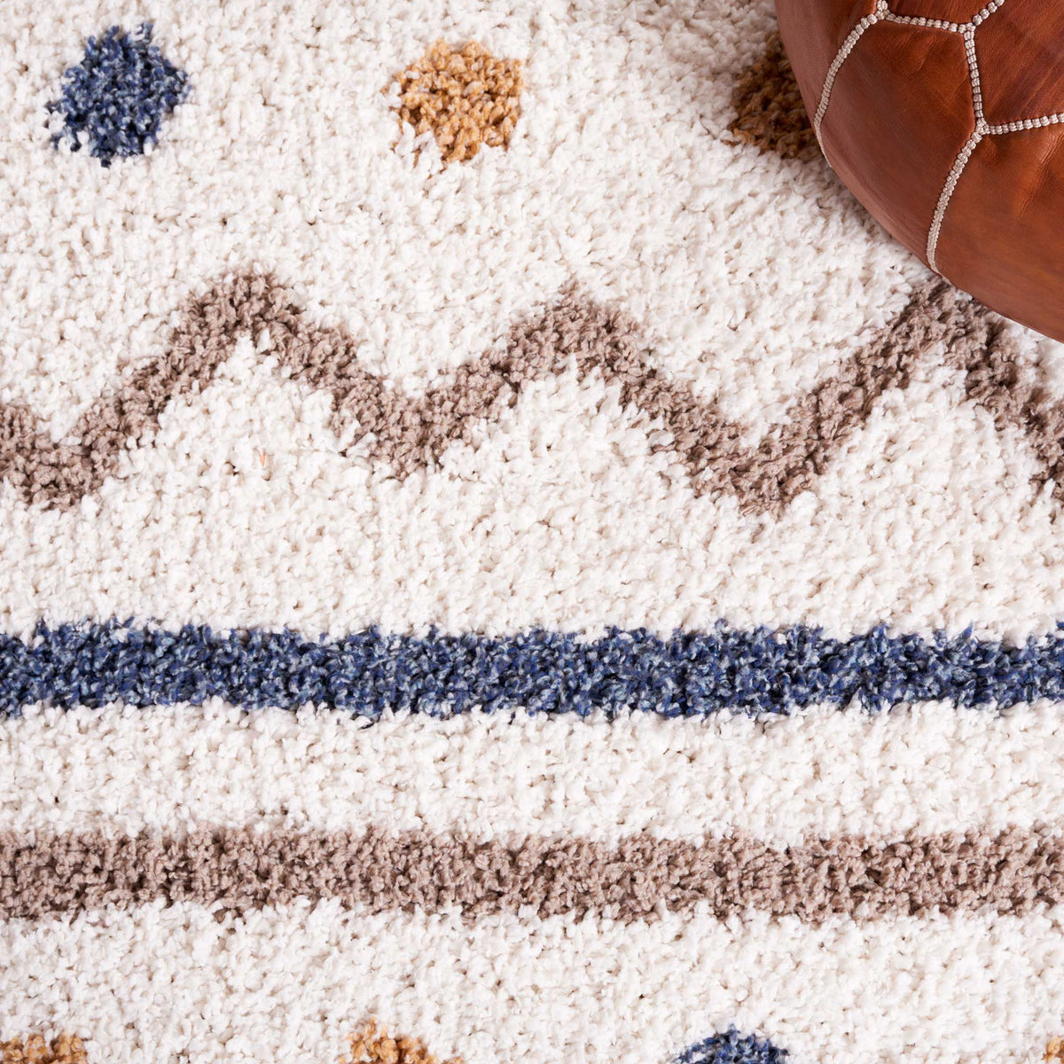 Blue lines, taupe chevrons, and golden dots animate thick ivory shag