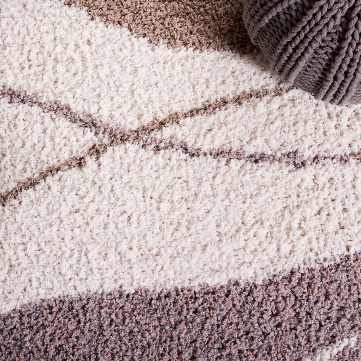 Winding lines sweep across ivory and taupe shag for gentle movement