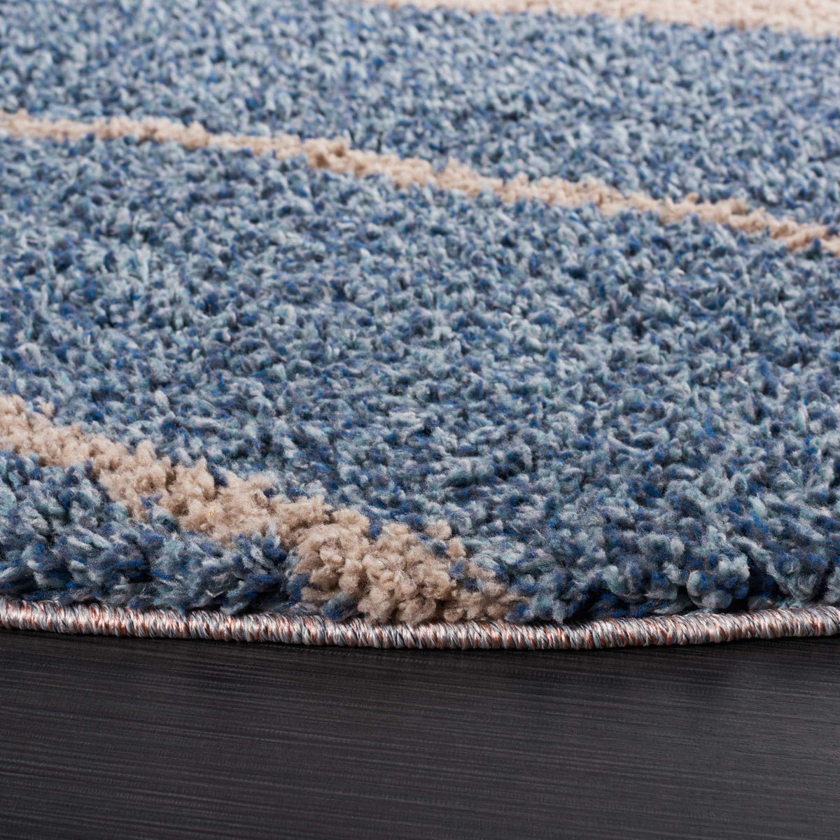 Soft blue and taupe shag fibers add depth to an abstract design with a bound edge