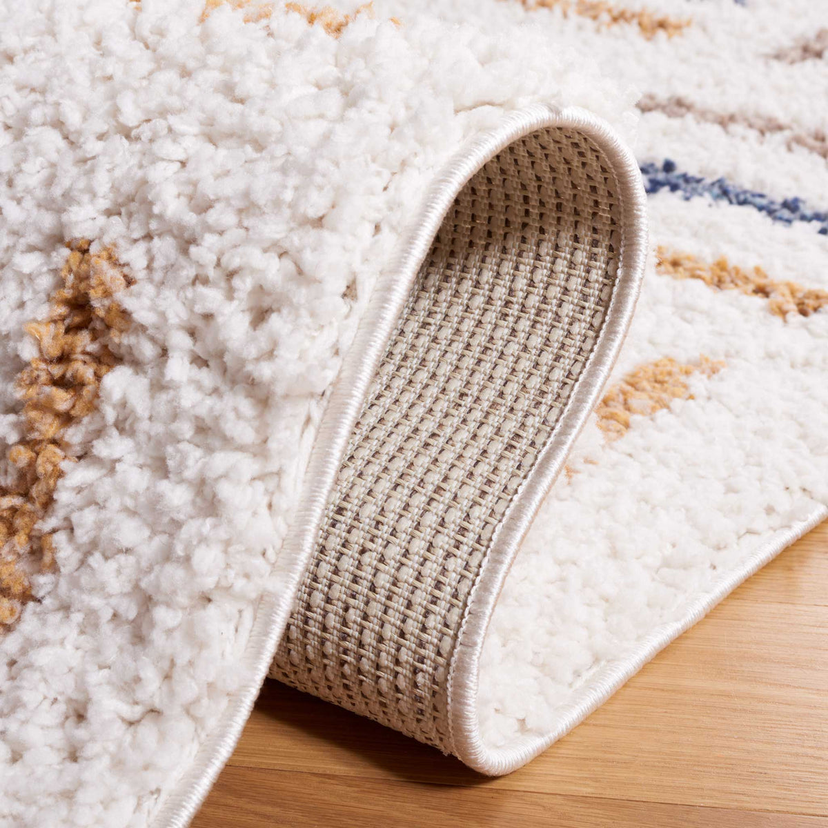 A turned-up ivory shag edge reveals the woven backing beneath it