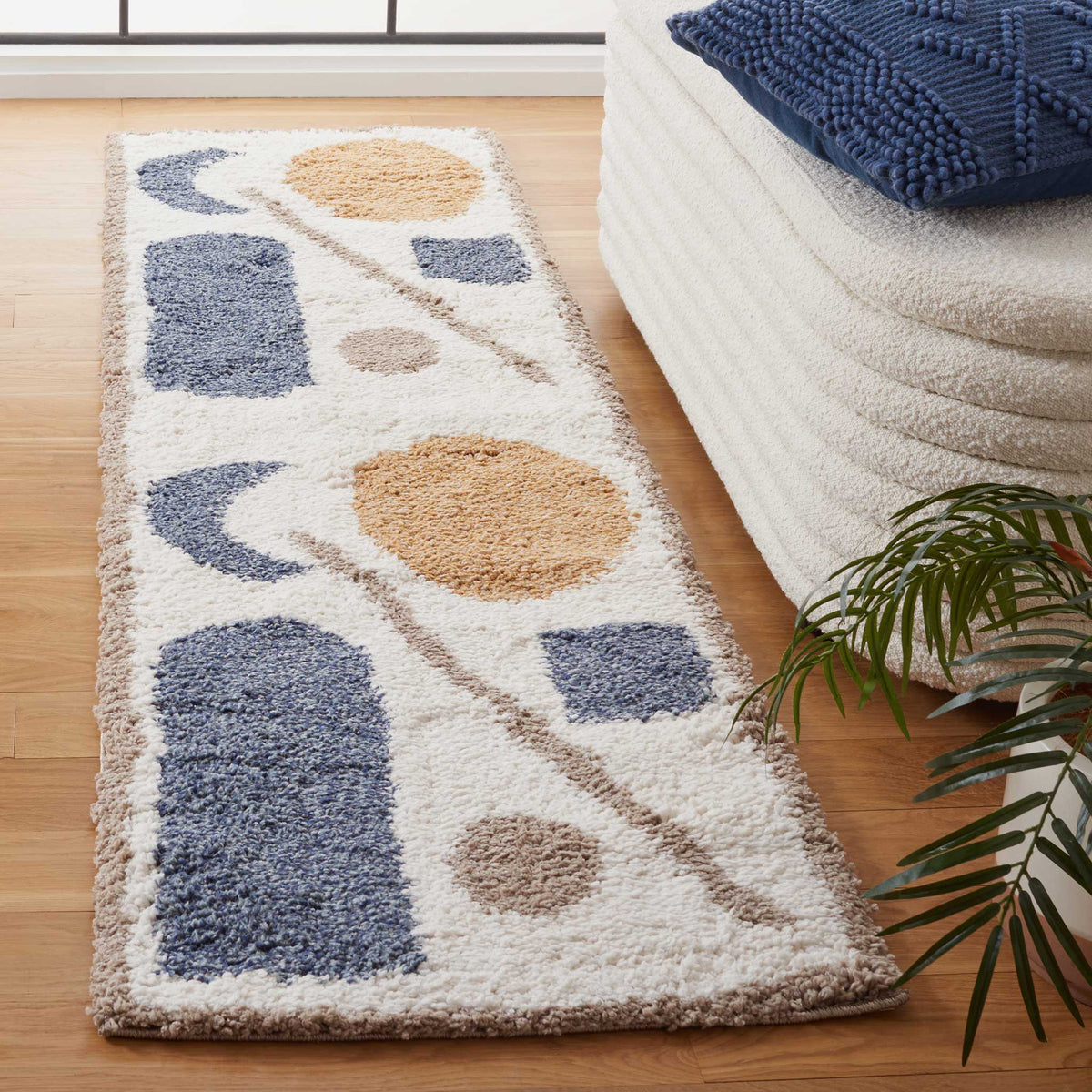 Plush pile makes the blue curves, golden circles, and taupe strokes stand out against ivory.