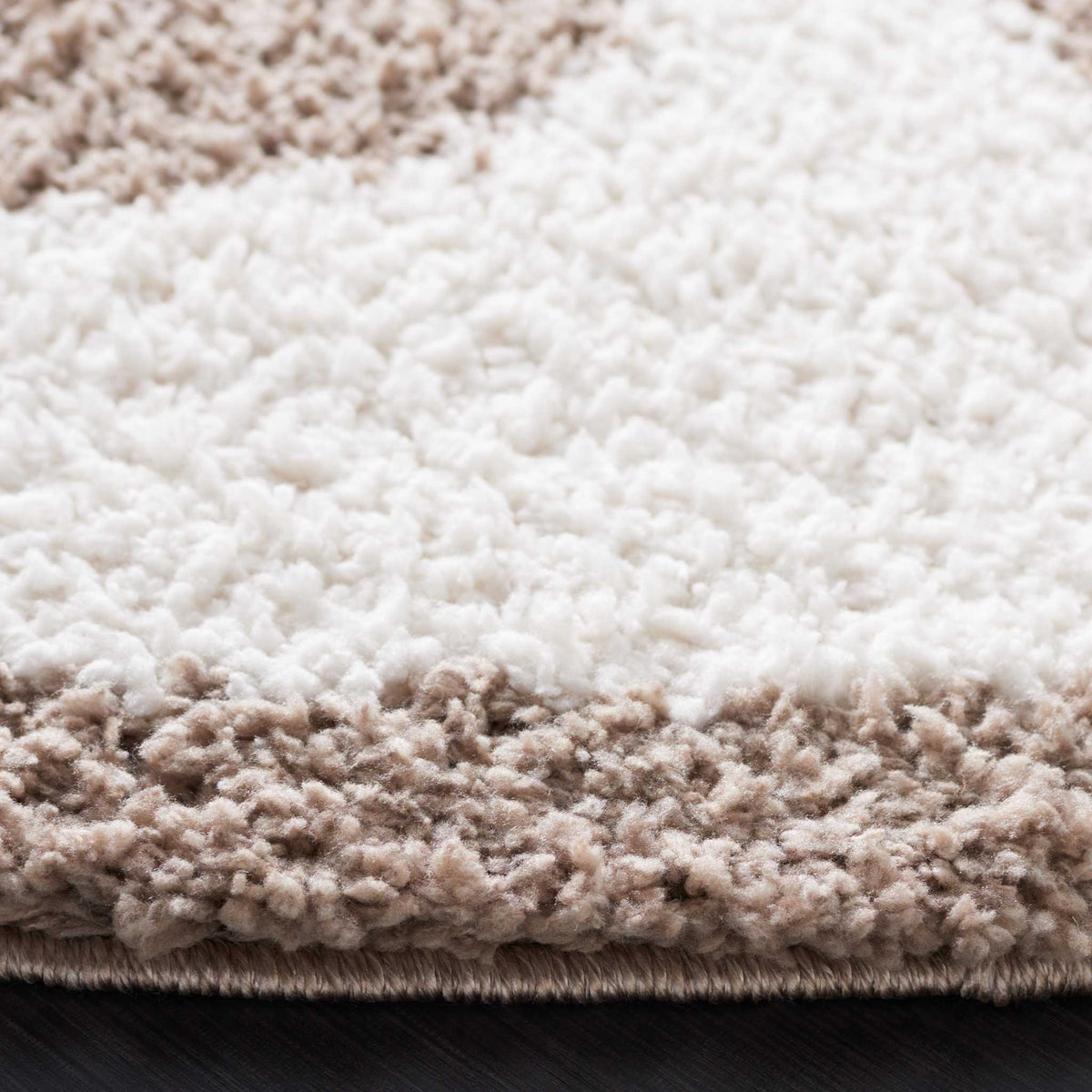 Plush ivory and taupe fibers meet at the thick, neatly bound edge