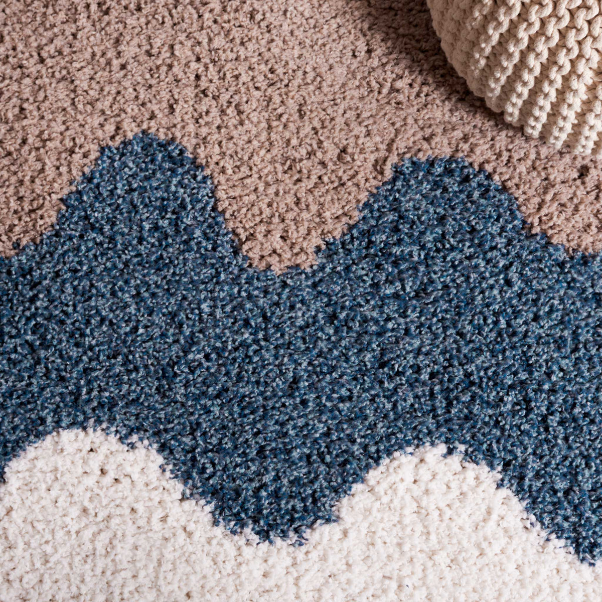 Rippling blue and taupe bands create soft contrast in a deep shag pile