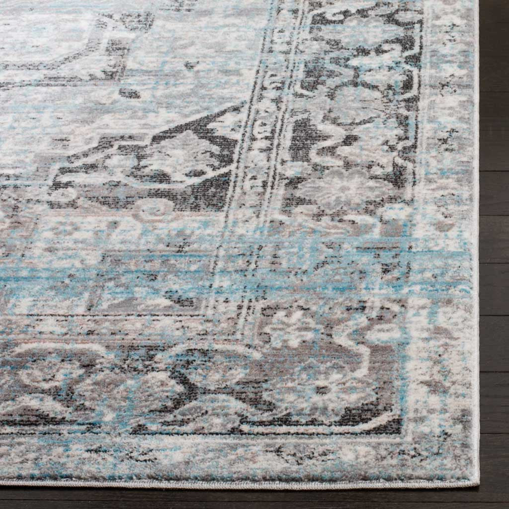 Soft, low-profile pile and bound edges frame the distressed floral border in ivory, gray, and blue.