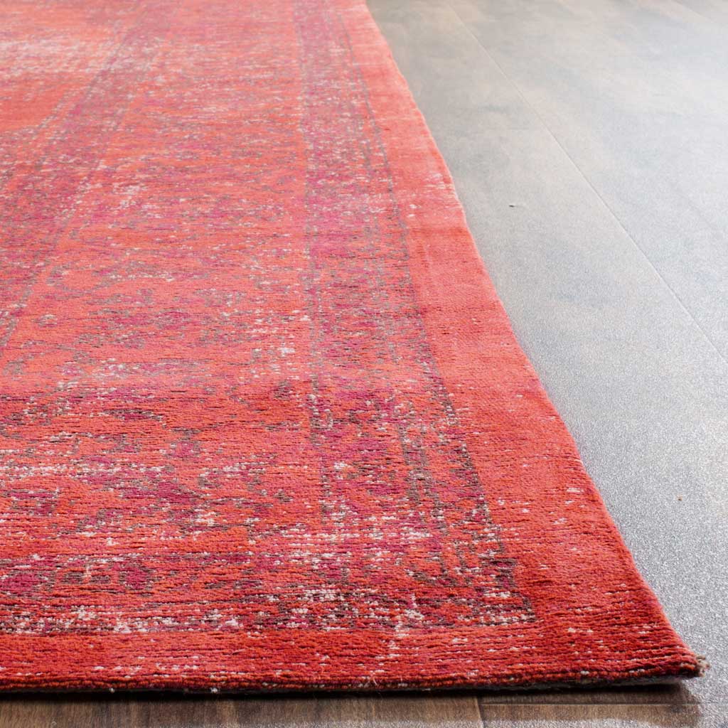 Bright orange-red pile and a shadowy floral border meet at a neatly finished edge.