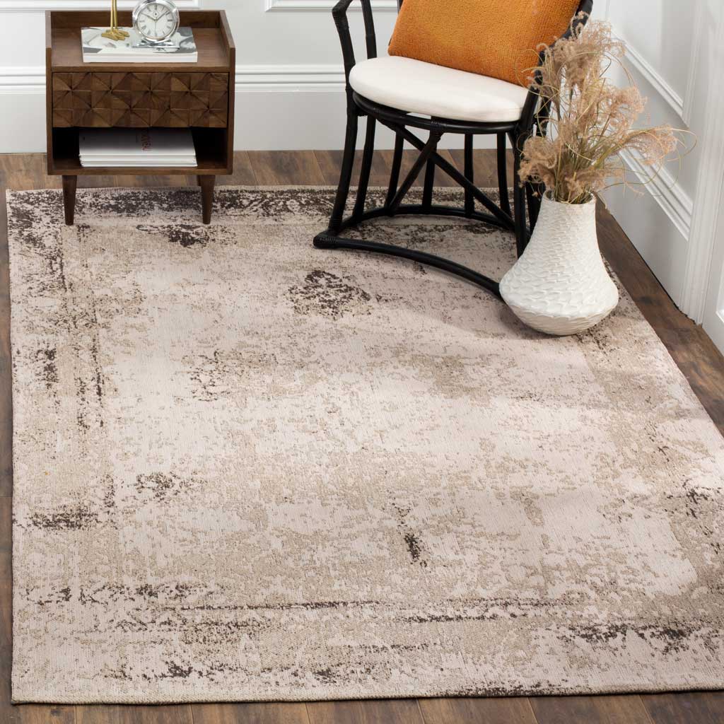A softly distressed neutral rug grounds a chair and side table with vintage-inspired charm.