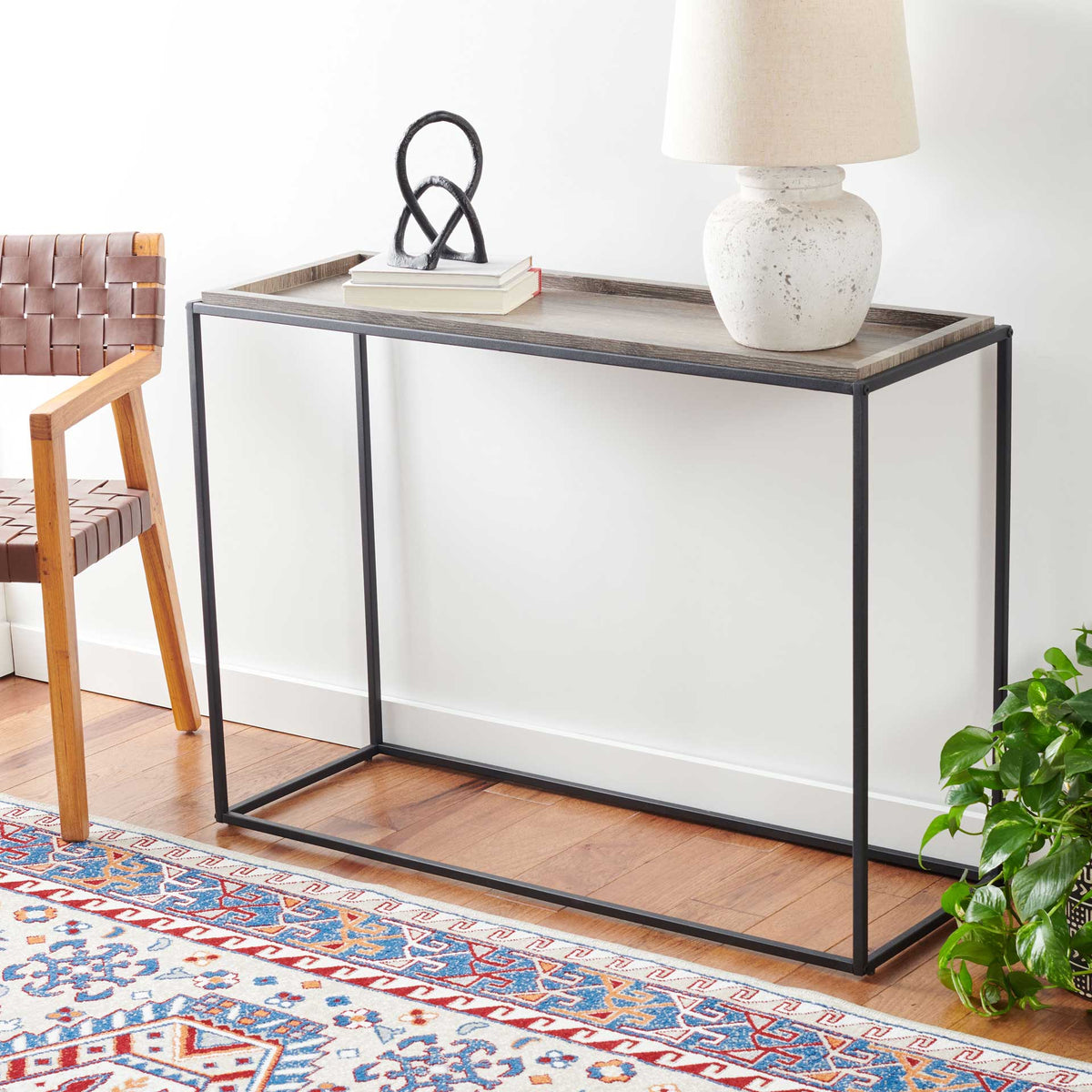 A raised wood-grain top displays books, sculpture, and a lamp above an open black frame