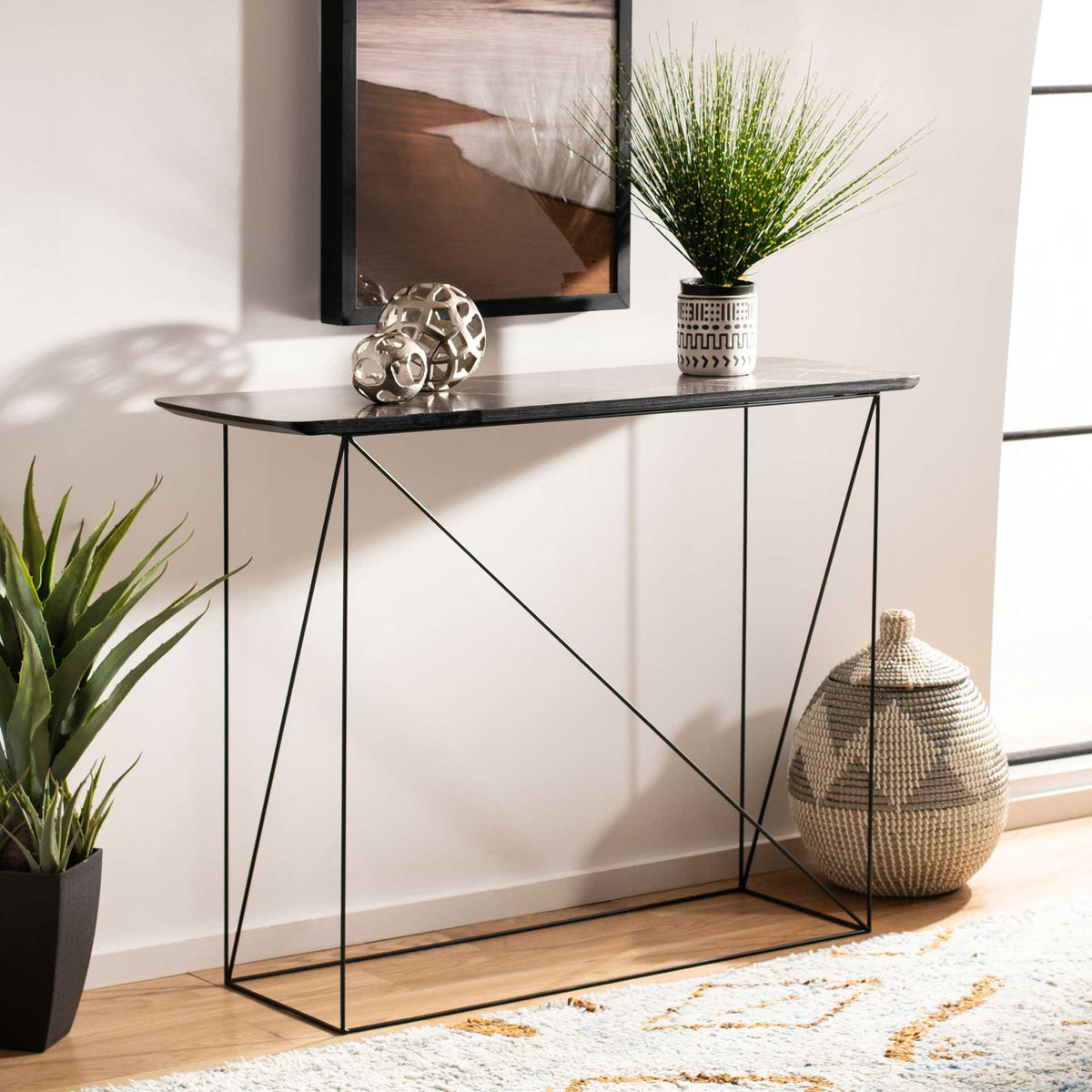 A warm-veined console top holds decorative accents above an airy geometric iron base
