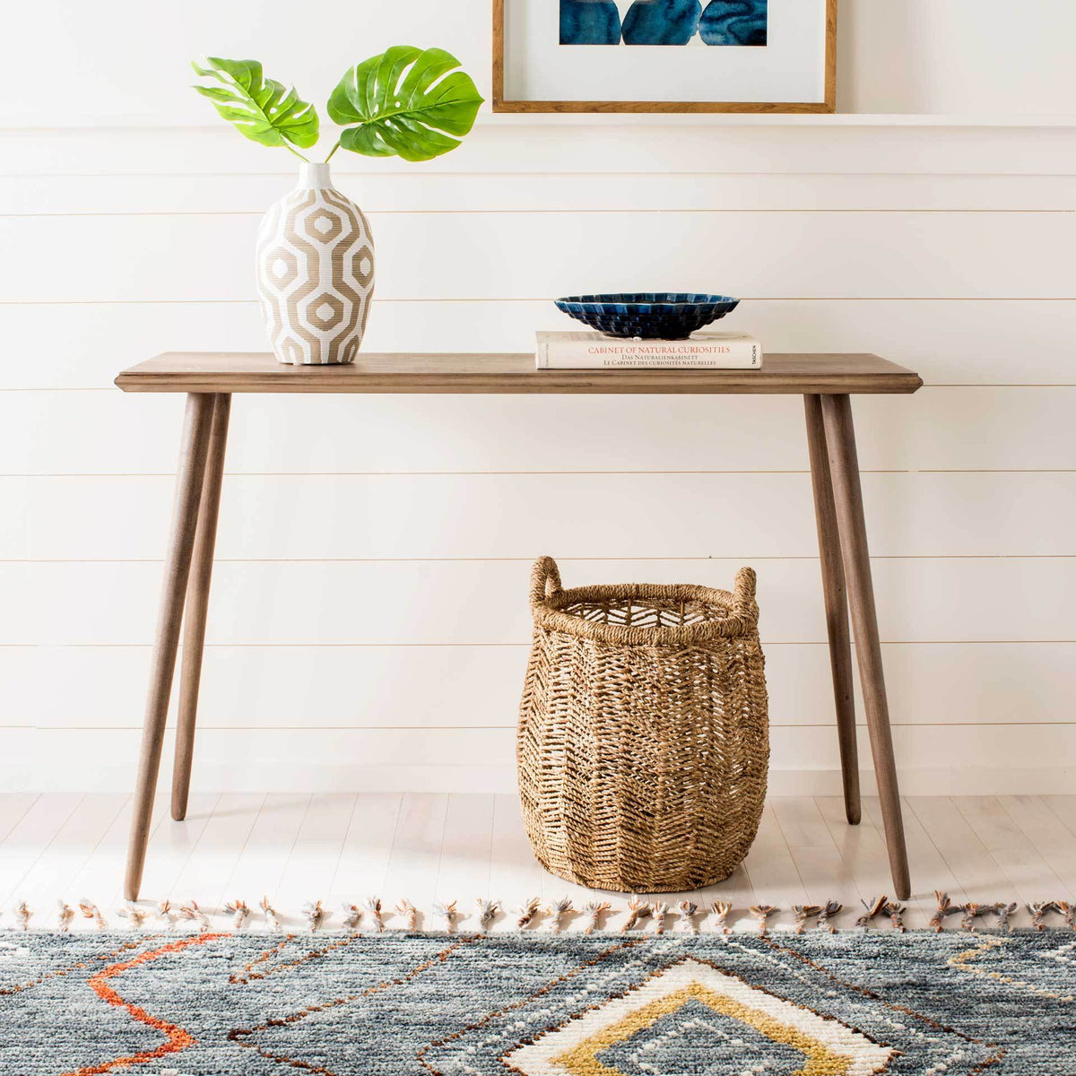 The light brown console table displays decorative accents with space for a basket beneath