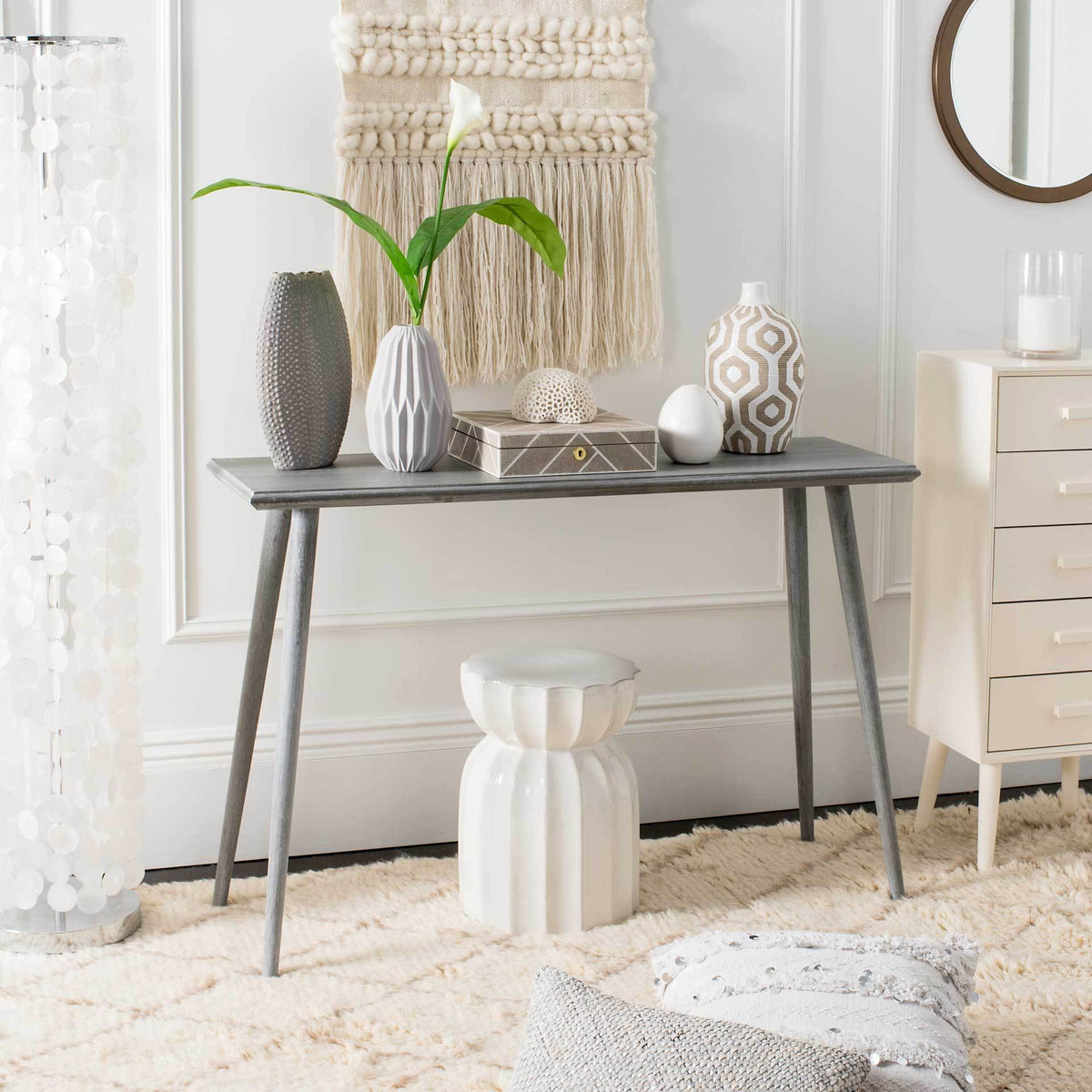 A slate gray console table displays vases and decorative accents above its open base
